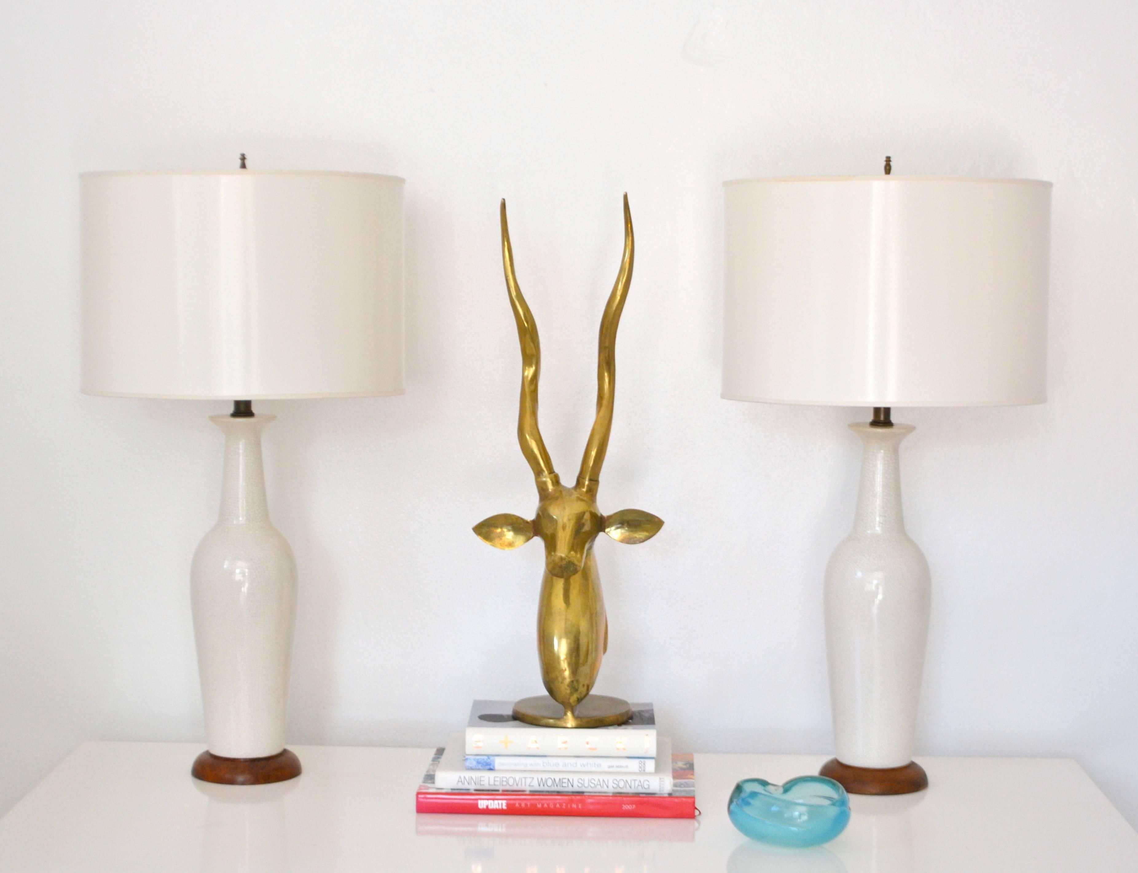 Striking pair of midcentury white crackle glazed ceramic bottle form table lamps, circa 1950s-1960s. These artisan crafted sculptural lamps are mounted on turned wood bases and wired with brass fittings. Shades not included.
Measurements: The