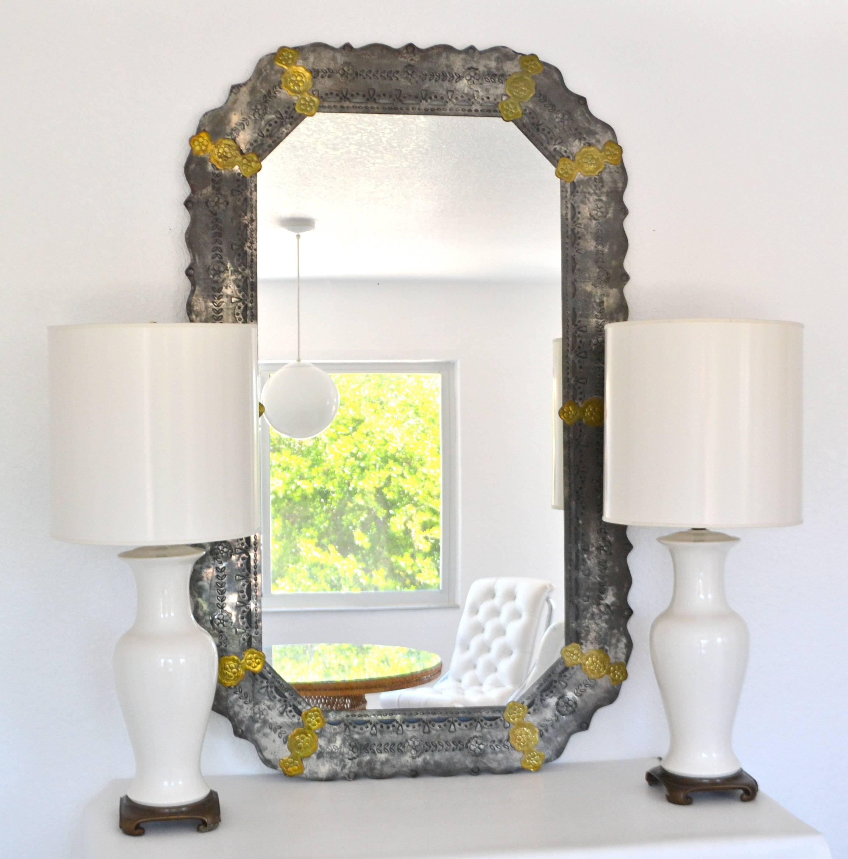 Stunning midcentury etched metal wall mirror, circa 1970s. This striking artisan crafted and highly decorative repousse metal mantel mirror is embellished with brass accents.