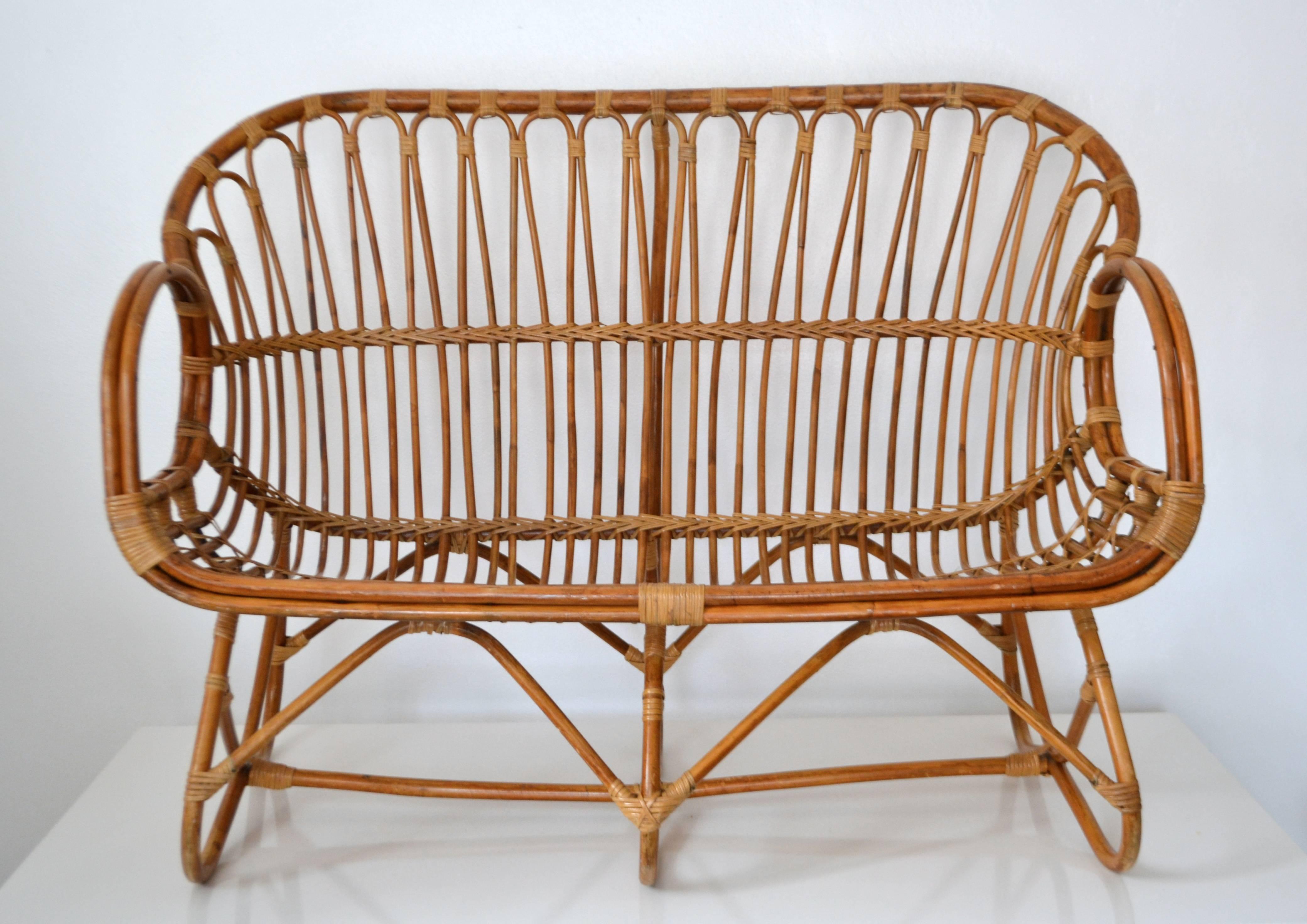 Striking midcentury bamboo settee, circa 1960s. This sculptural artisan crafted love seat is designed of bent bamboo with cane accents.