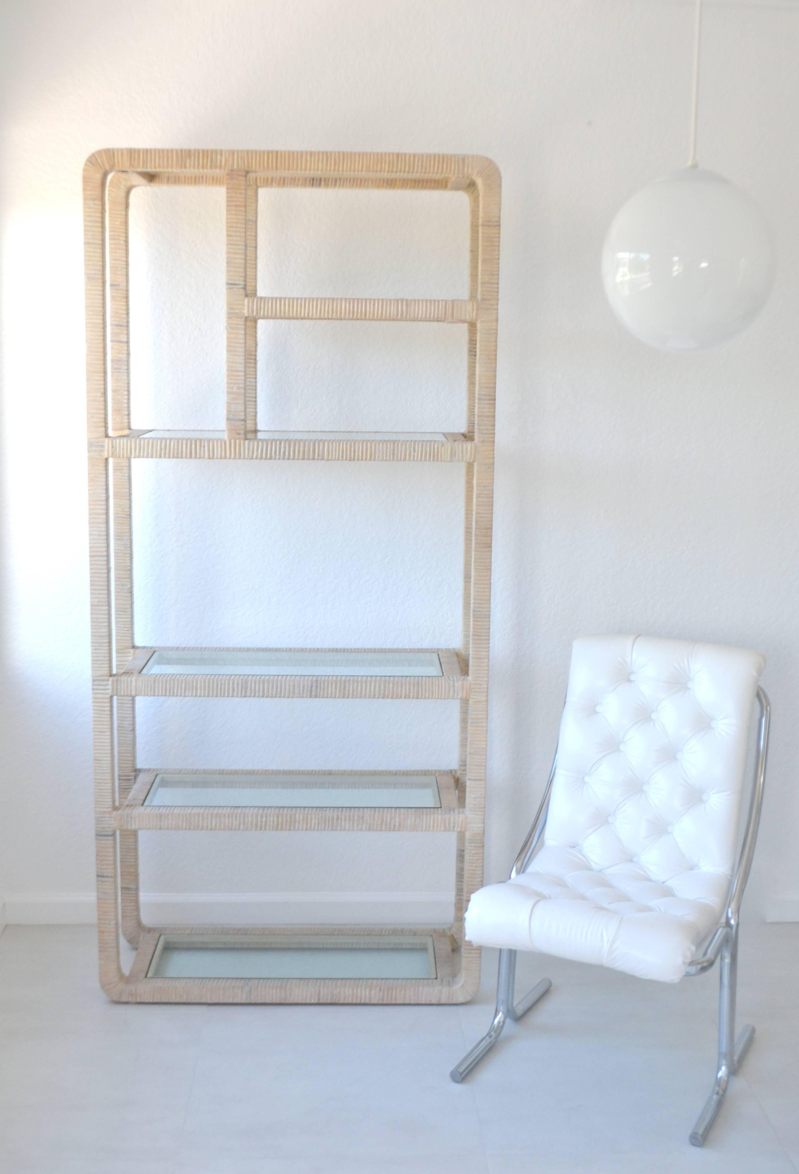 Striking Mid-Century whitewashed rattan etagere, circa 1960s-1970s. This sculpturally designed rattan wrapped hardwood bookcase or bookshelf is accented with inset glass shelves.