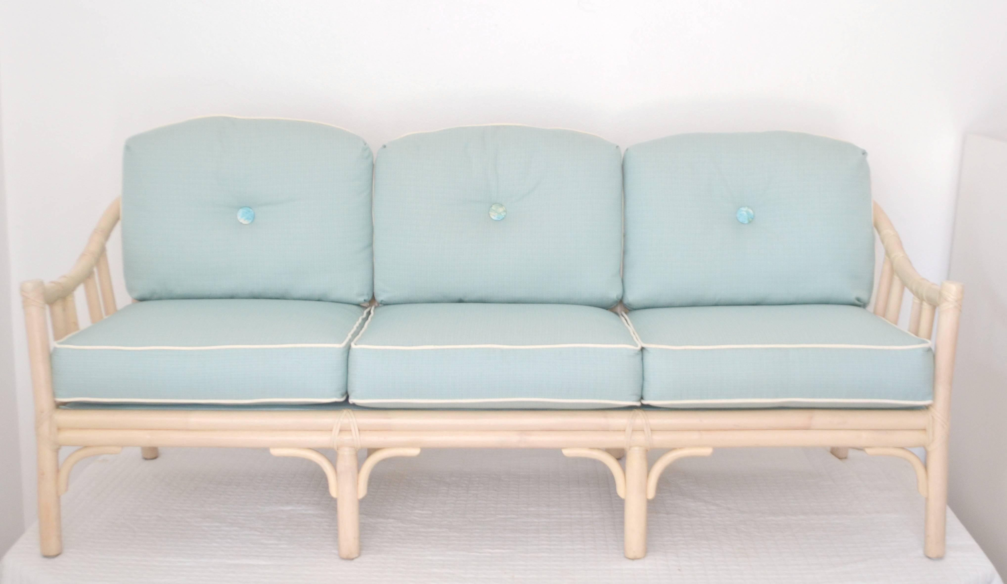 Mid-Century bamboo and leather wrapped three-seat sofa or settee by McGuire, circa 1960s-1970s. This artisan crafted whitewashed bamboo framed settee is accented with azure blue cushions finished with a contrasting white welt.