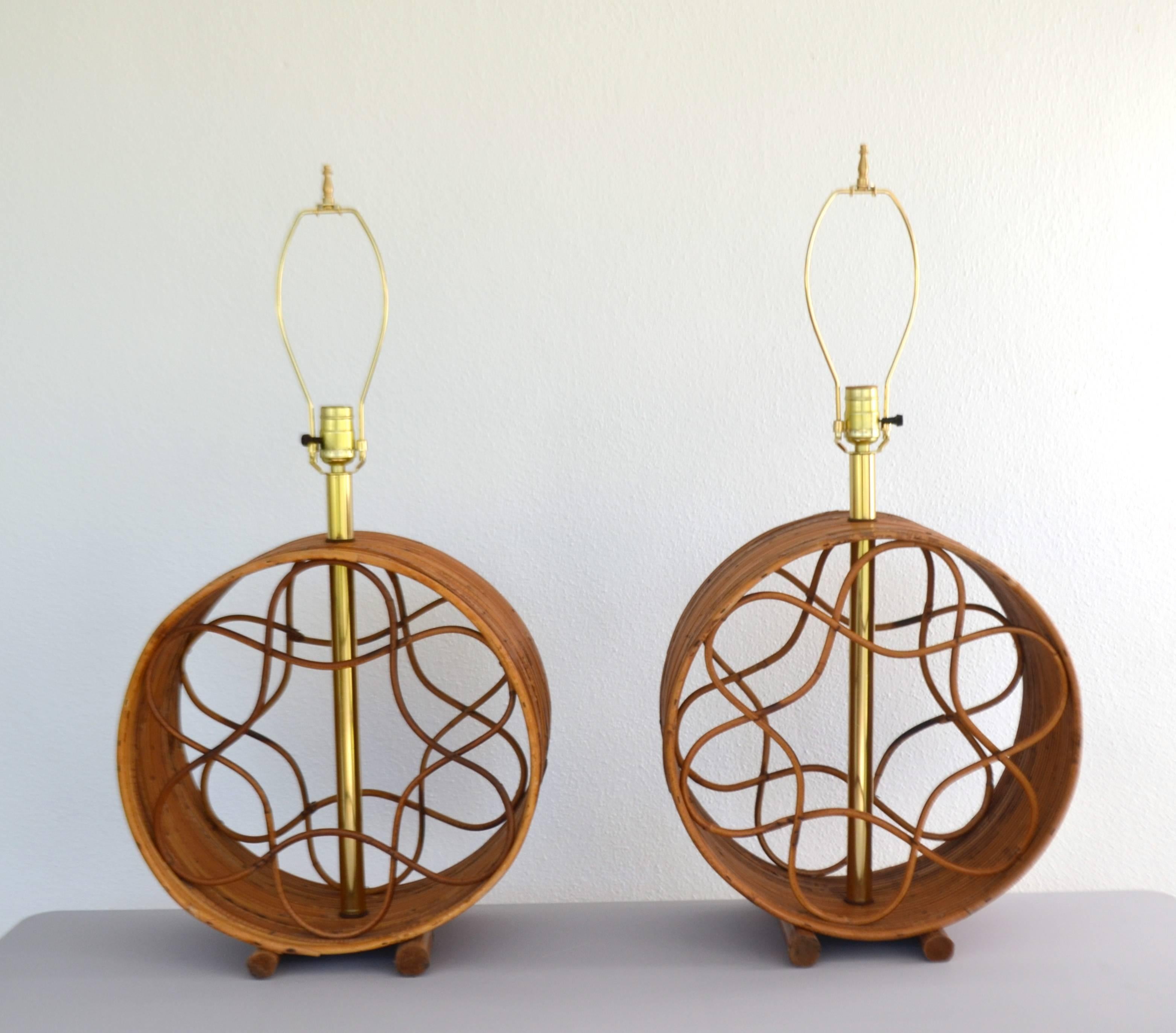 Sculptural pair of Mid-Century reed and bamboo circular form table lamps, circa 1960s. These stunning lamps are designed of graphic twisted reed elements mounted in bent bamboo forms. Lamps have been rewired with brass fittings. Shades not