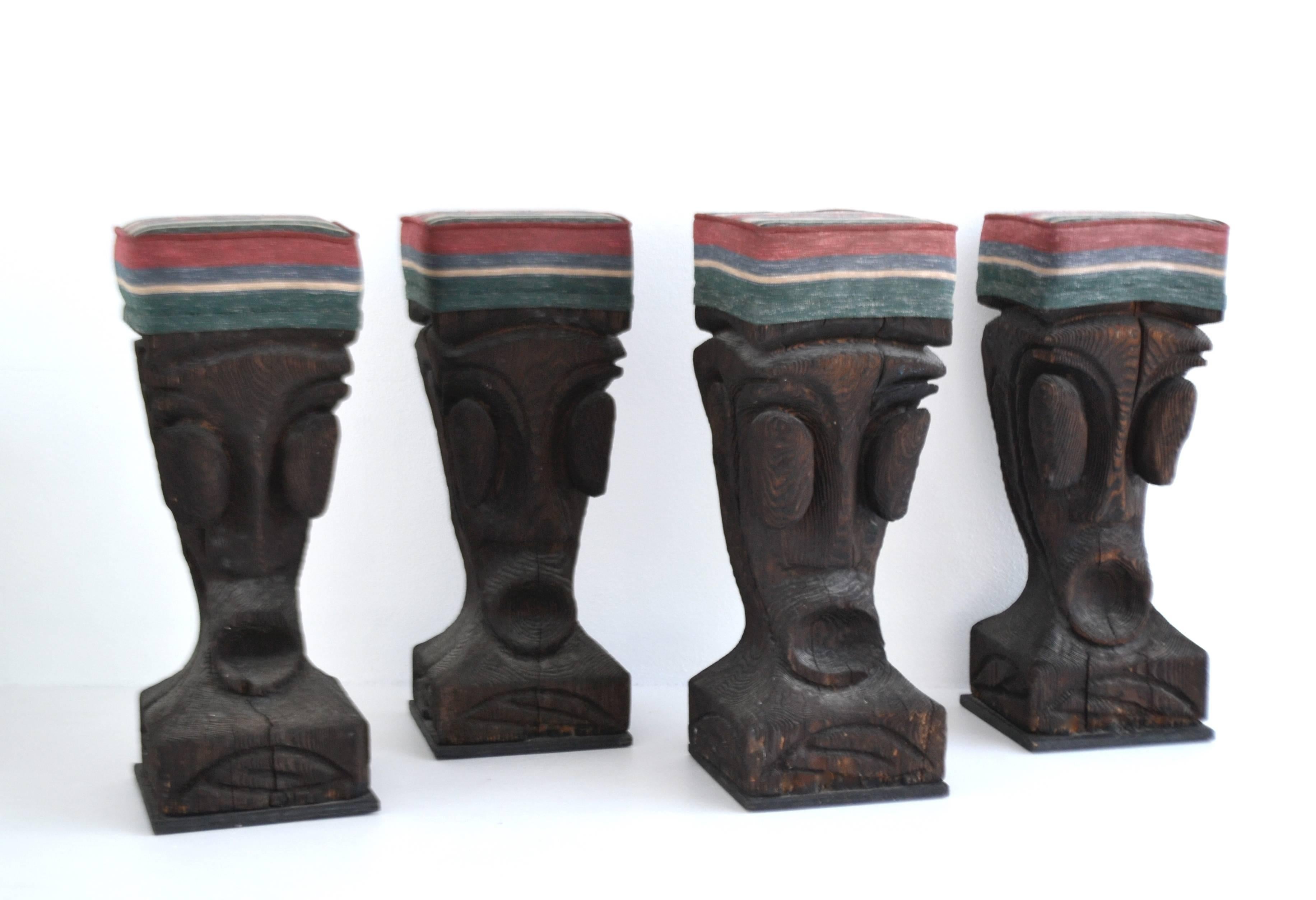 Set of four Brutalist wooden bar stools, circa 1960s-1970s. These sculptural pop Primitive carved stools are artisan crafted with seats upholstered in cotton linen fabric.