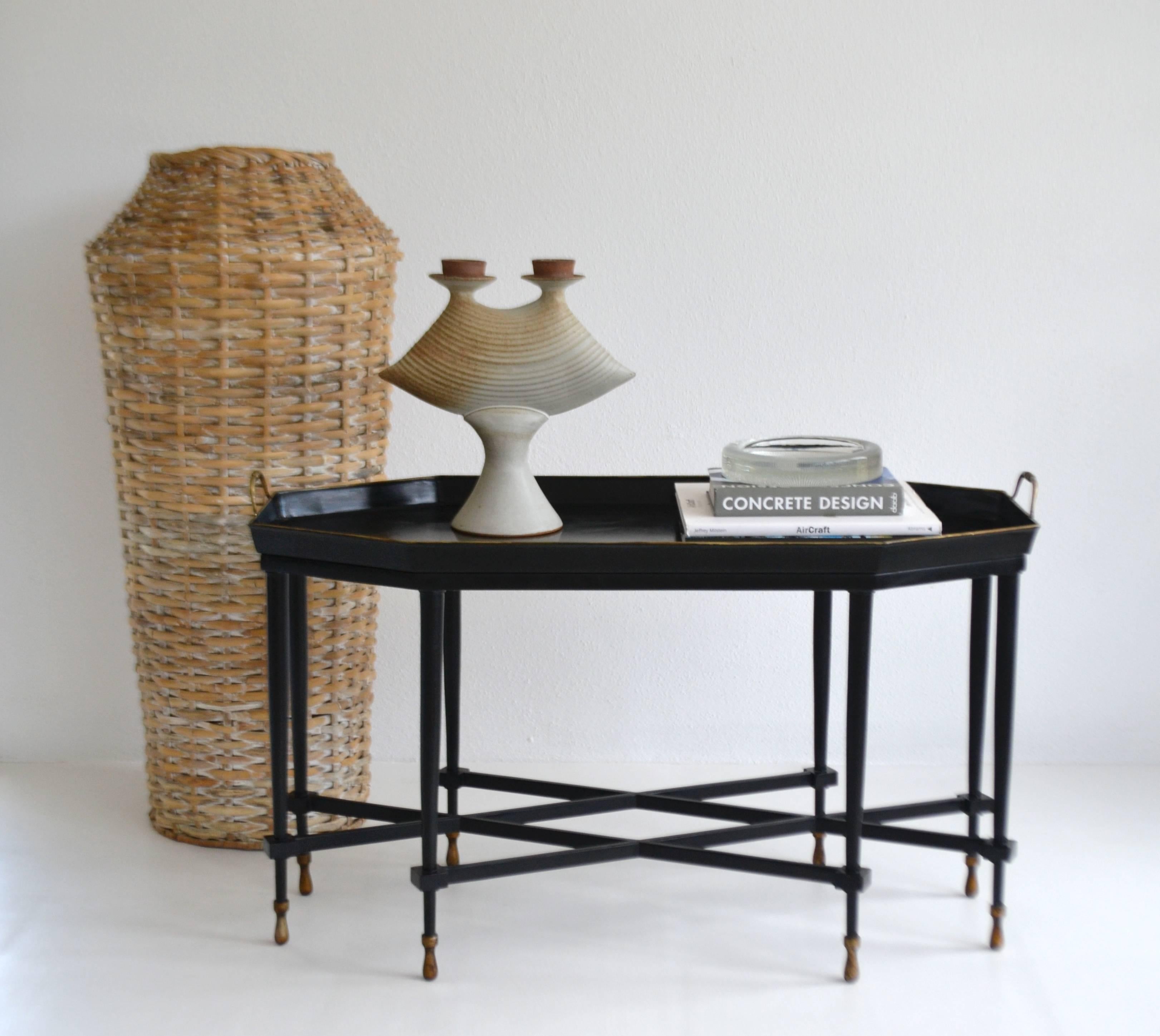 Glamorous Hollywood Regency style tole tray top cocktail table, circa 1960s-1970s. This striking coffee table is artisan crafted of black lacquered tole with gilt accents. The table is designed with a removable octagonal tray top mounted on an eight
