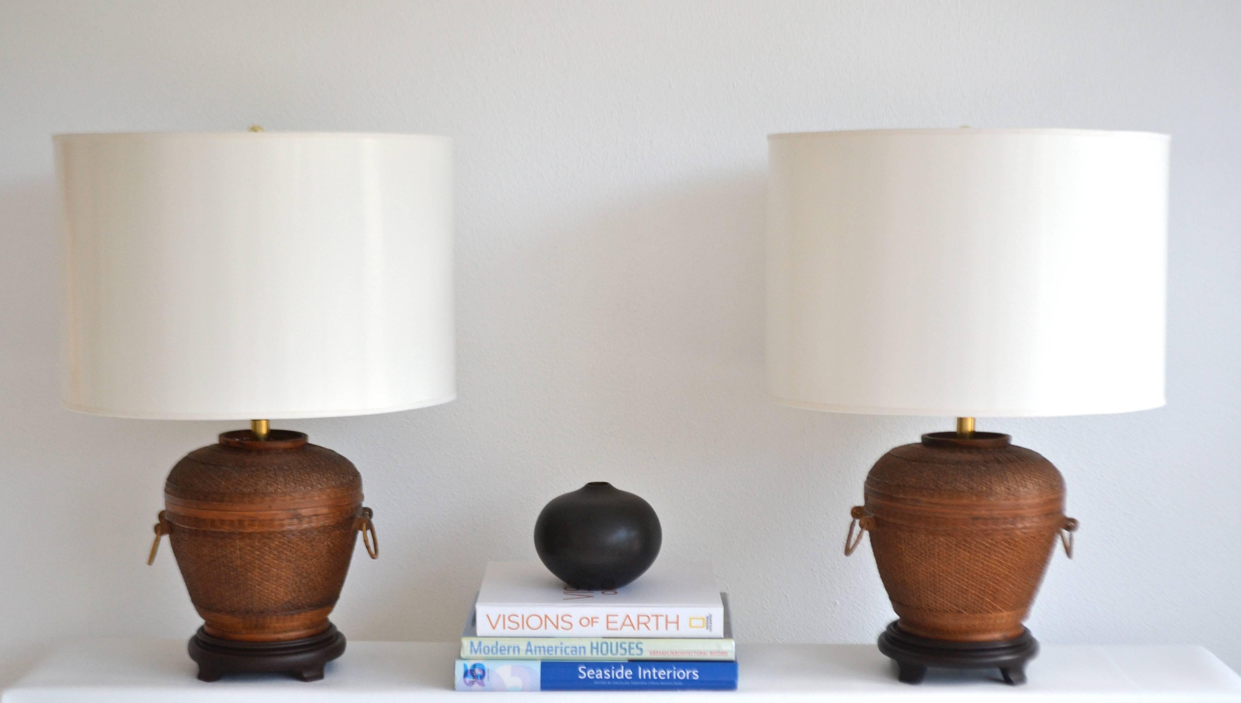 Striking pair of Mid-Century woven reed basket form table lamps, circa 1950s-1960s. These sculptural lamps are mounted on carved hardwood bases and wired with brass fittings.
Shades not included.
Measurements: Overall dimensions: 25