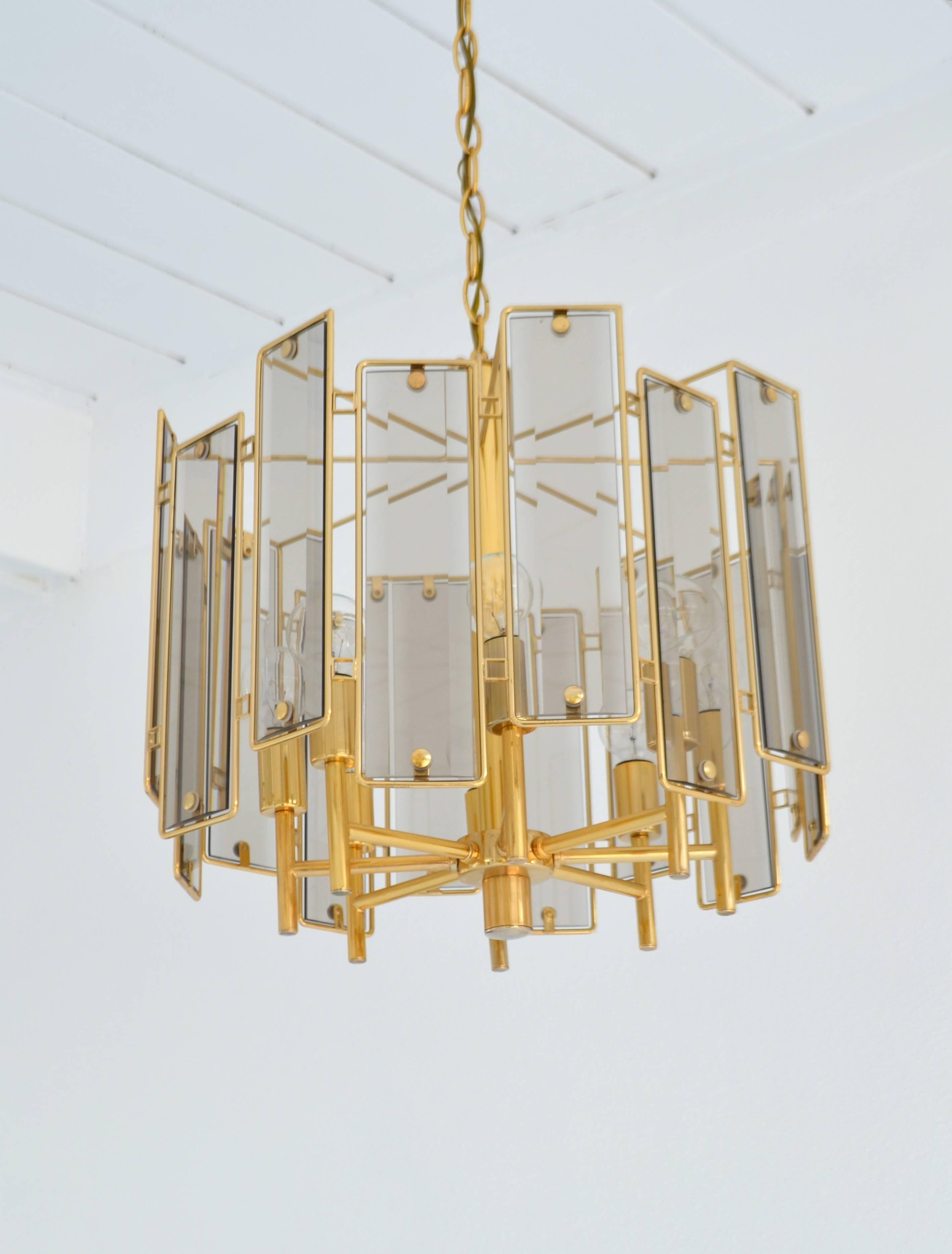 Sculptural midcentury Italian brass eight-arm chandelier, circa 1970s-1980s. This striking chandelier is designed with eight brass candlestick arms surrounded by inset beveled glass reflective panels framed in brass.
Bulbs not included. 60 watt