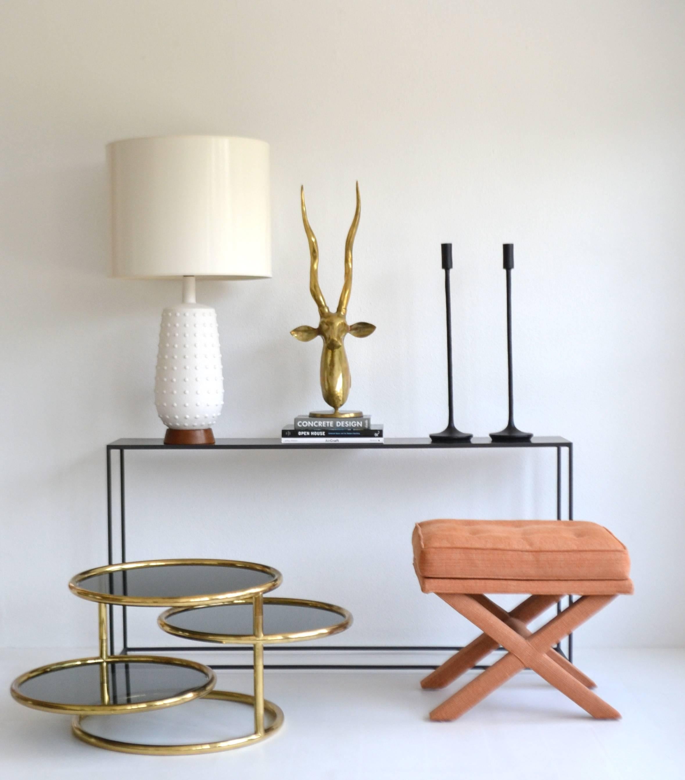 Striking Postmodern three-tier articulating side table, circa 1980s. This sculptural end table / occasional table is finished in polished brass and accented with tinted inset glass tops. The table is designed for the middle two tiers to swivel