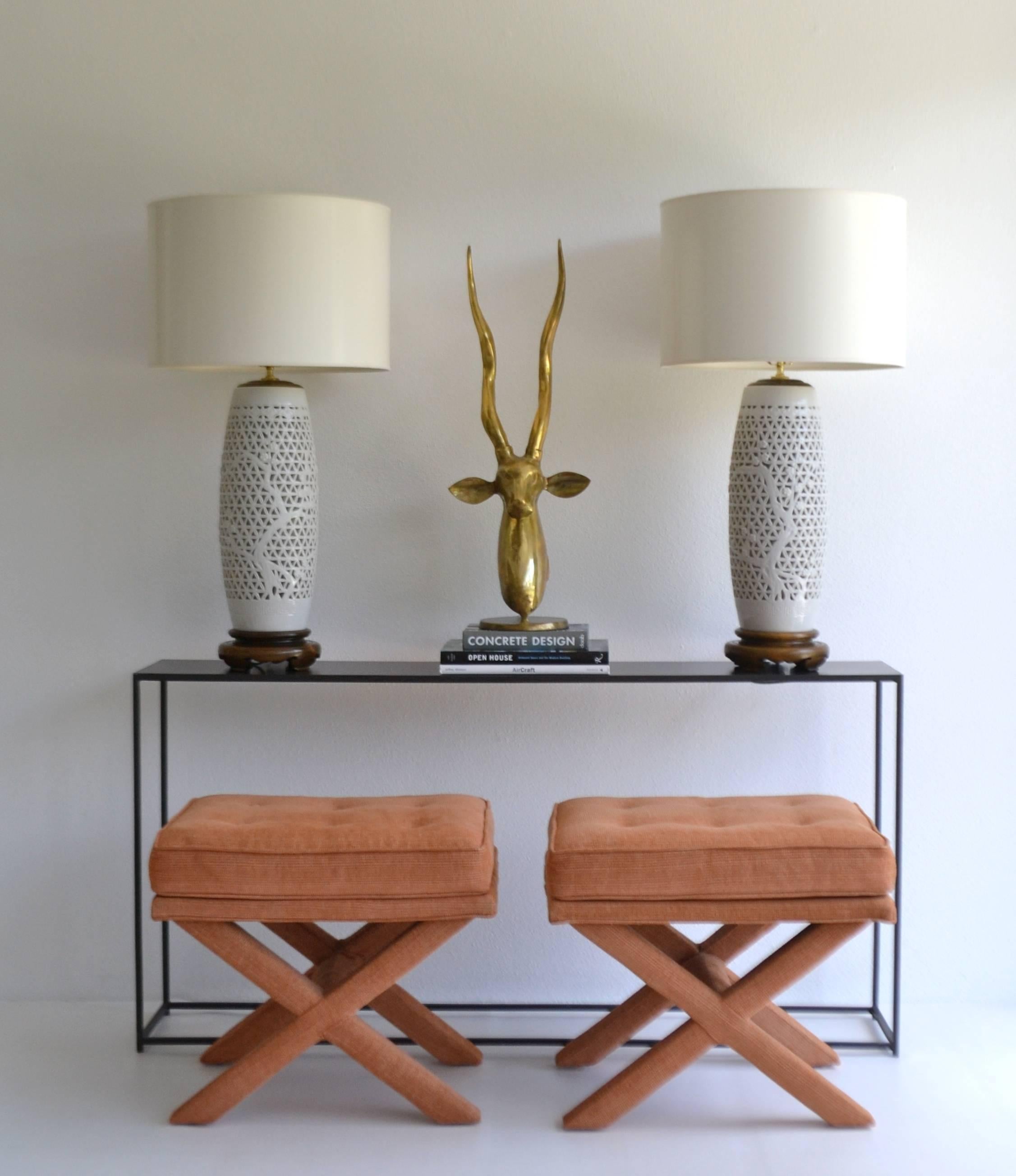 Glamorous pair of Hollywood Regency Asian inspired reticulated Blanc de Chine table lamps, circa 1940s -1950s. These incredible pierced porcelain white glazed table lamps are accented with foliate decoration and mounted on carved wooden bases and