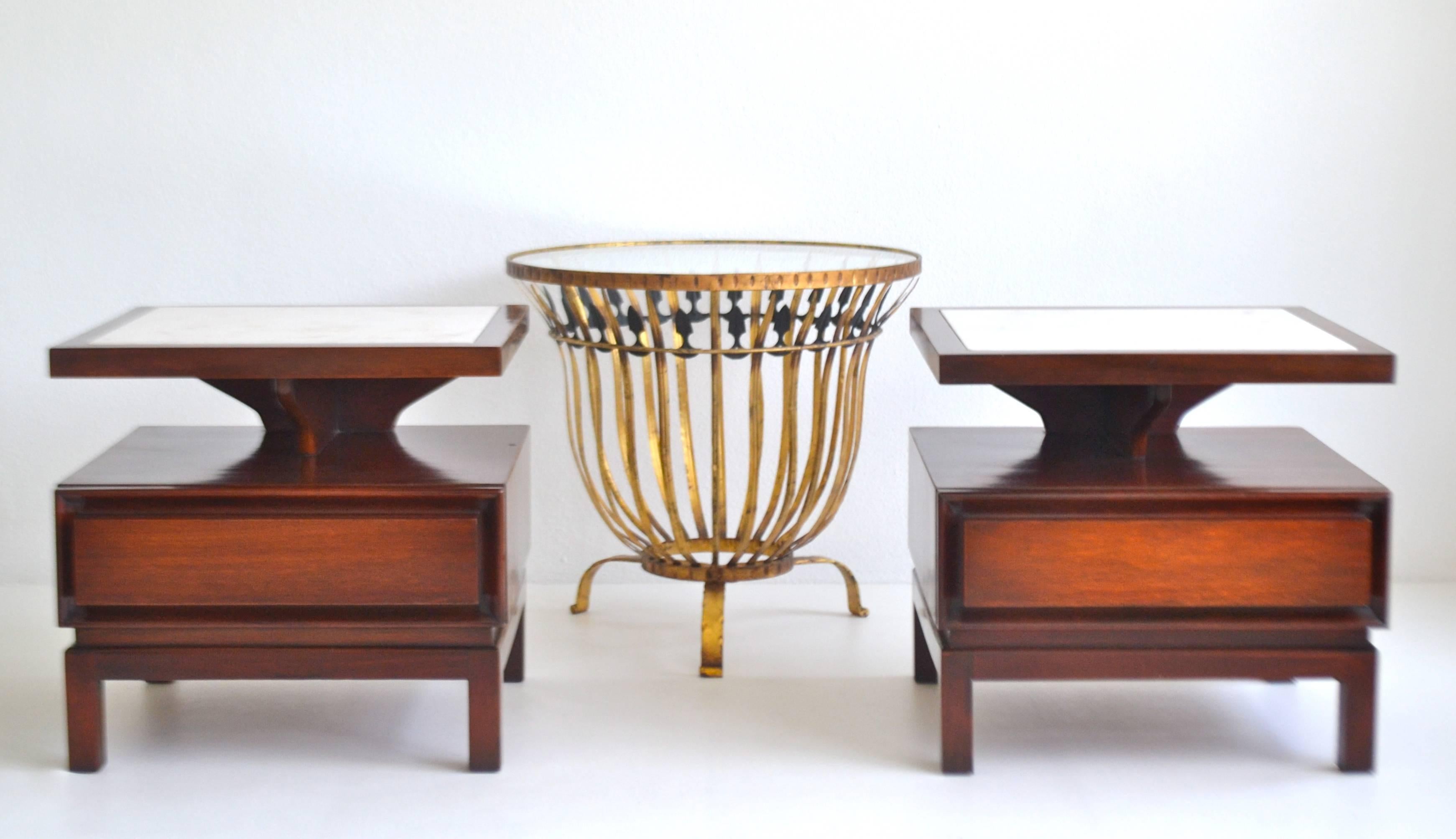 Striking pair of midcentury sculptural two-tier side tables, circa 1950s-1960s. These Art Deco inspired artisan crafted end tables are designed with a floating top tier over a single drawer base. The bedside tables are outfitted with inset white