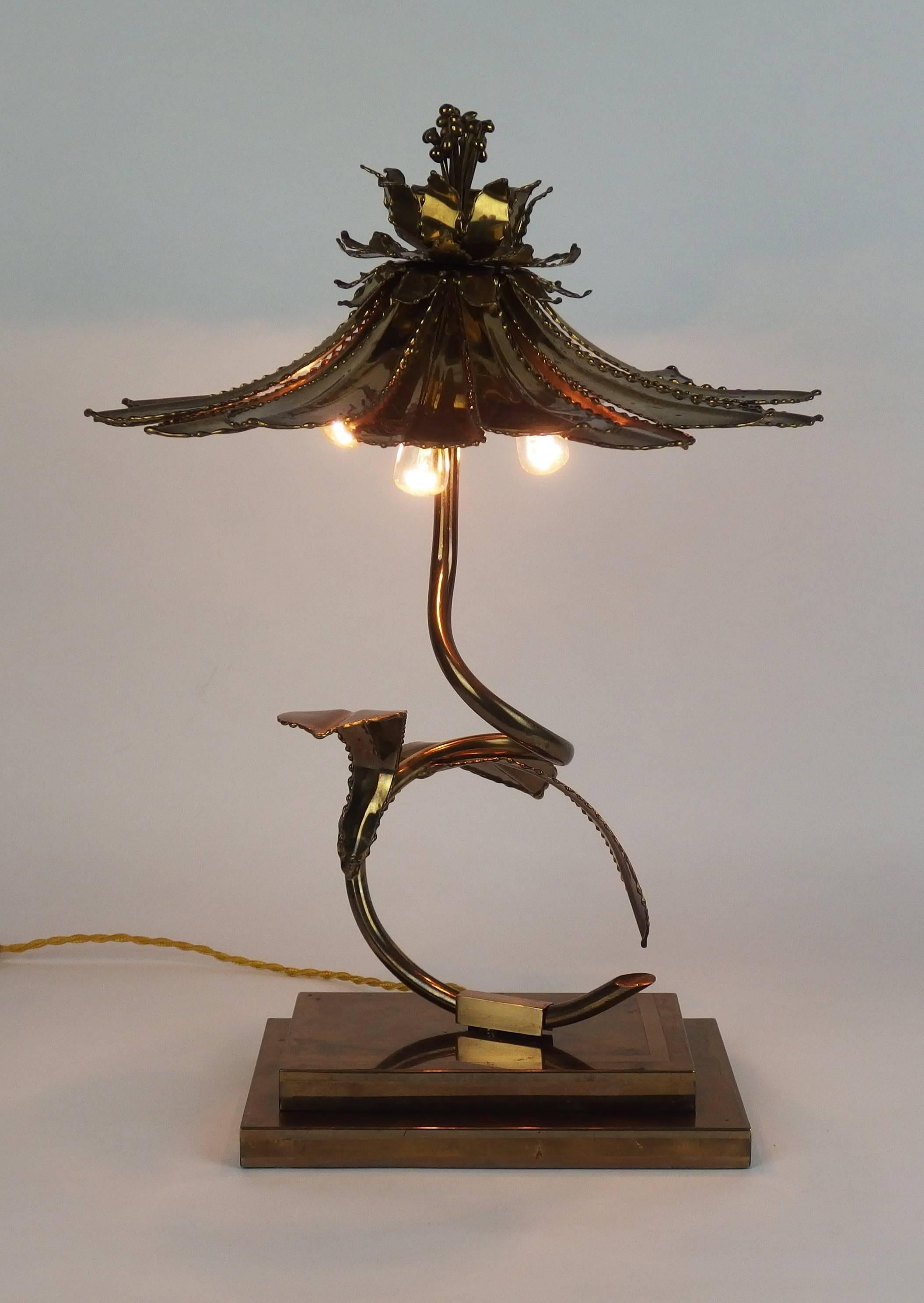 An  brass flower table lamp whith a shade  made up of brass petals fixed on the stem with a stamens shape piece.3 bulbs under the shade.