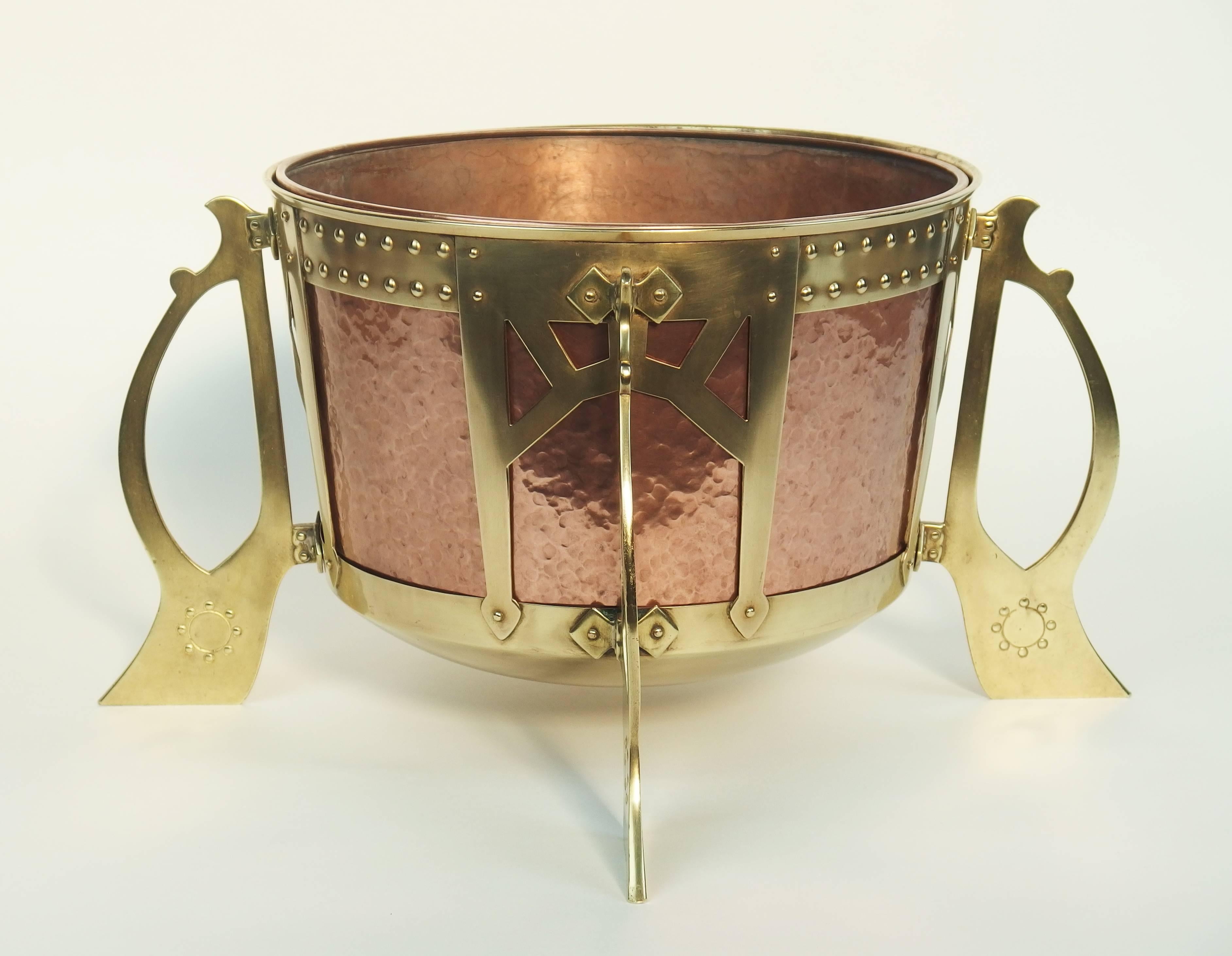 A typical Jugendstil style planter with a removable copper bowl in a brass structure with four handles, signed under the bowl.