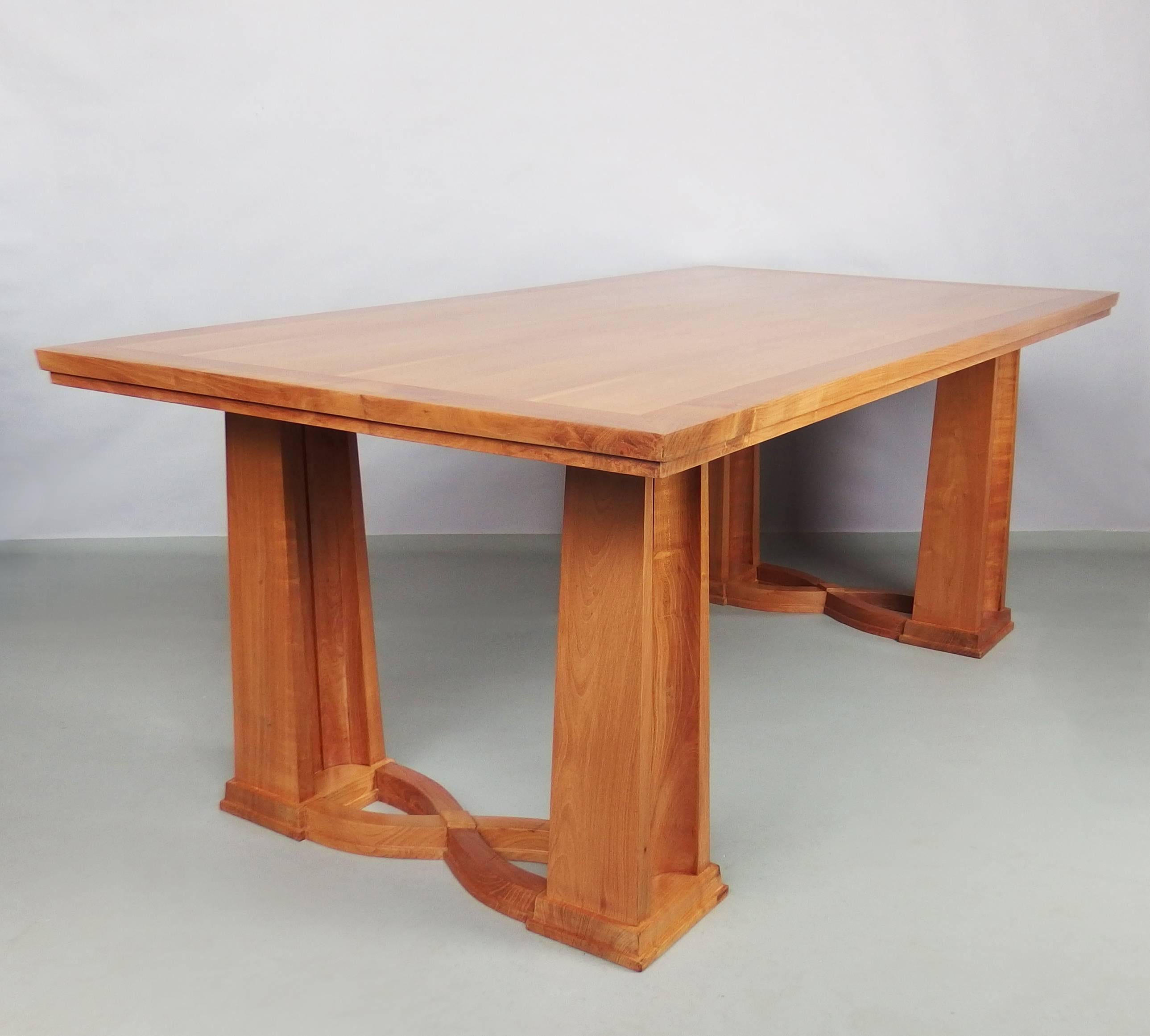 A fine dining or writing table in cherrywood with curved lines on feet and pedestals.
