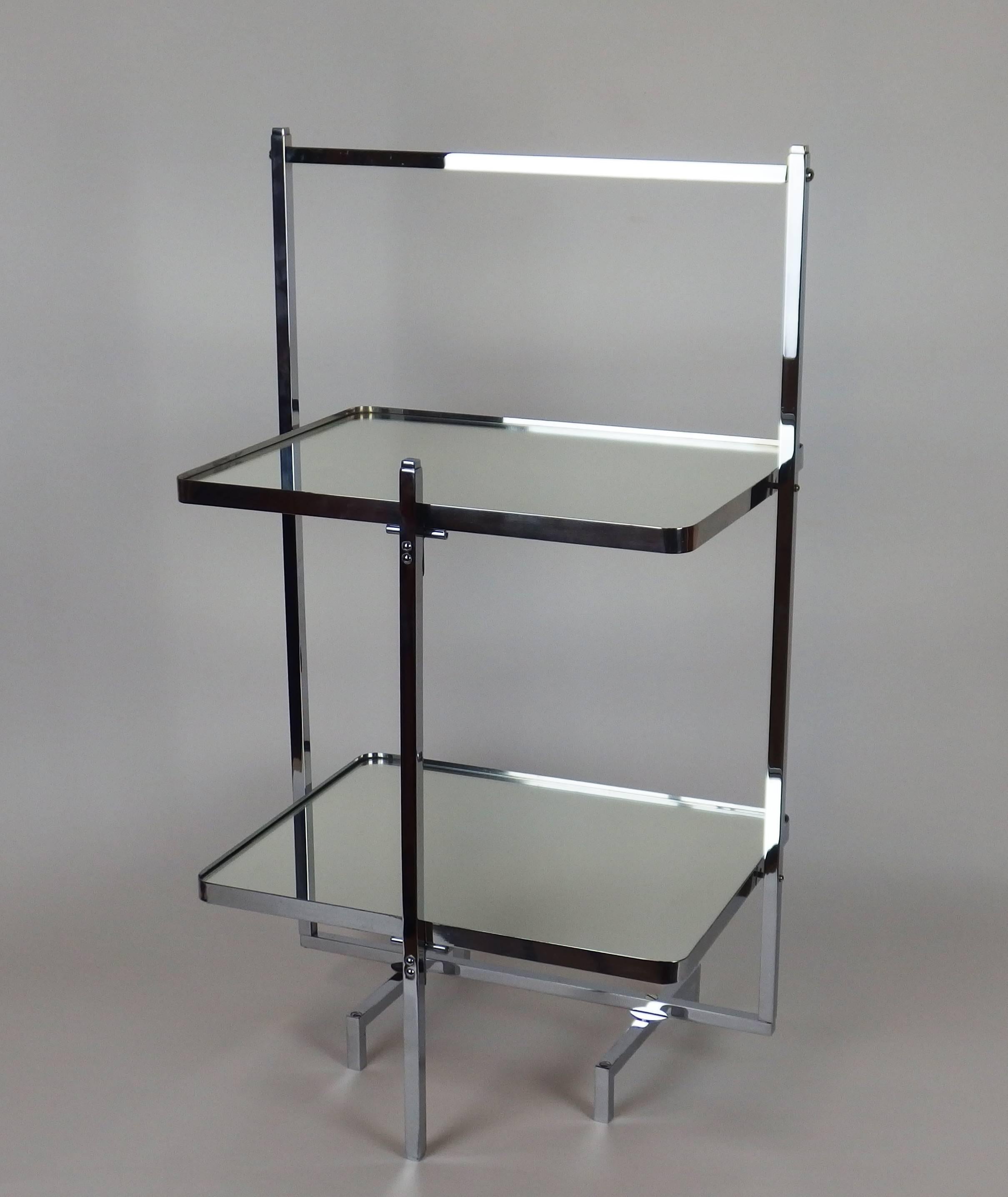A chromed metal and mirrored glass dessert table with two rectangular trays pivoting on an angular support to fold the table.