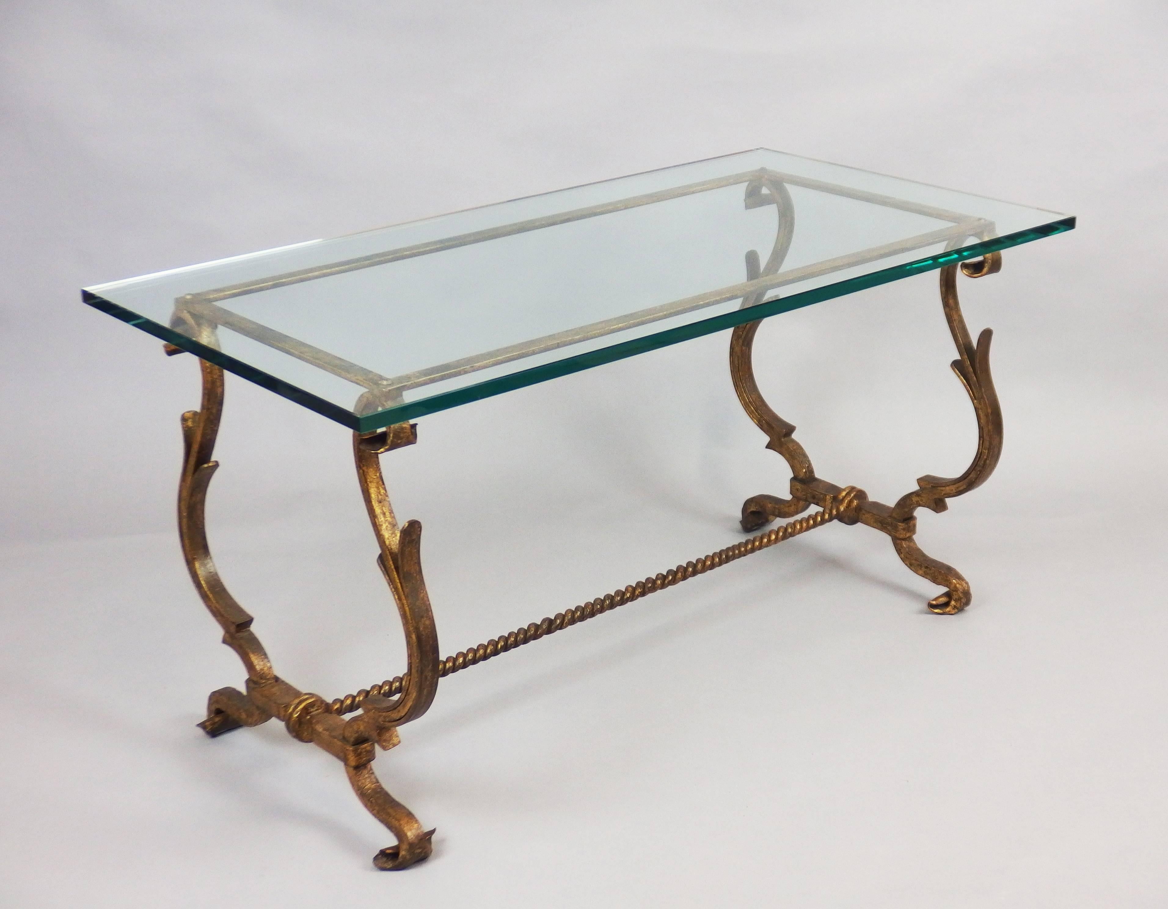 1940s wrought iron table with a gilt patina and a translucent glass top.