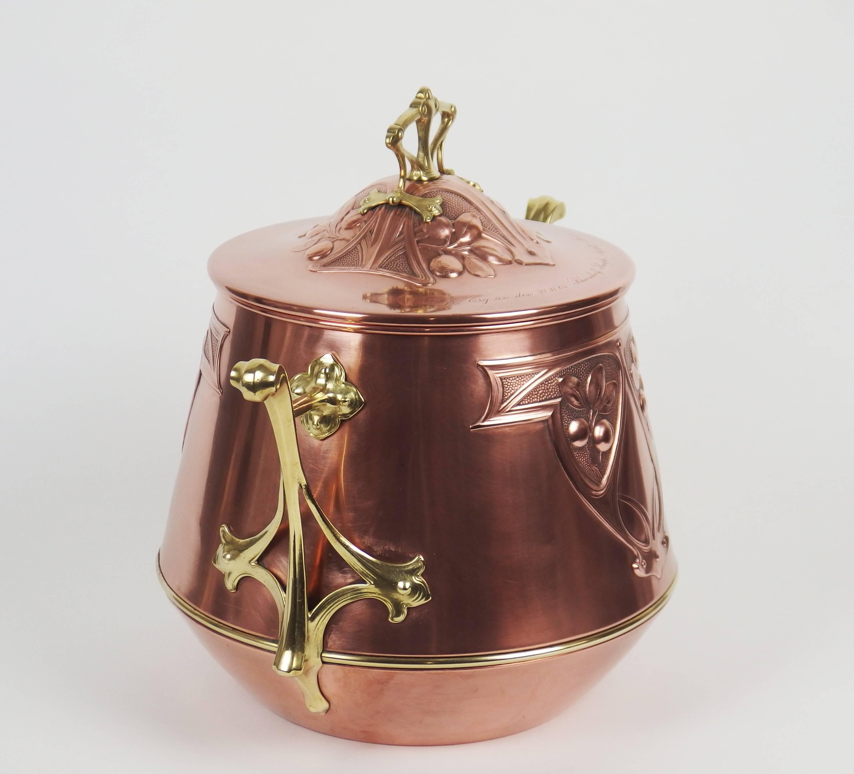 A brass and copper covered pot with flowers patterns and memorial inscriptions on the lid: