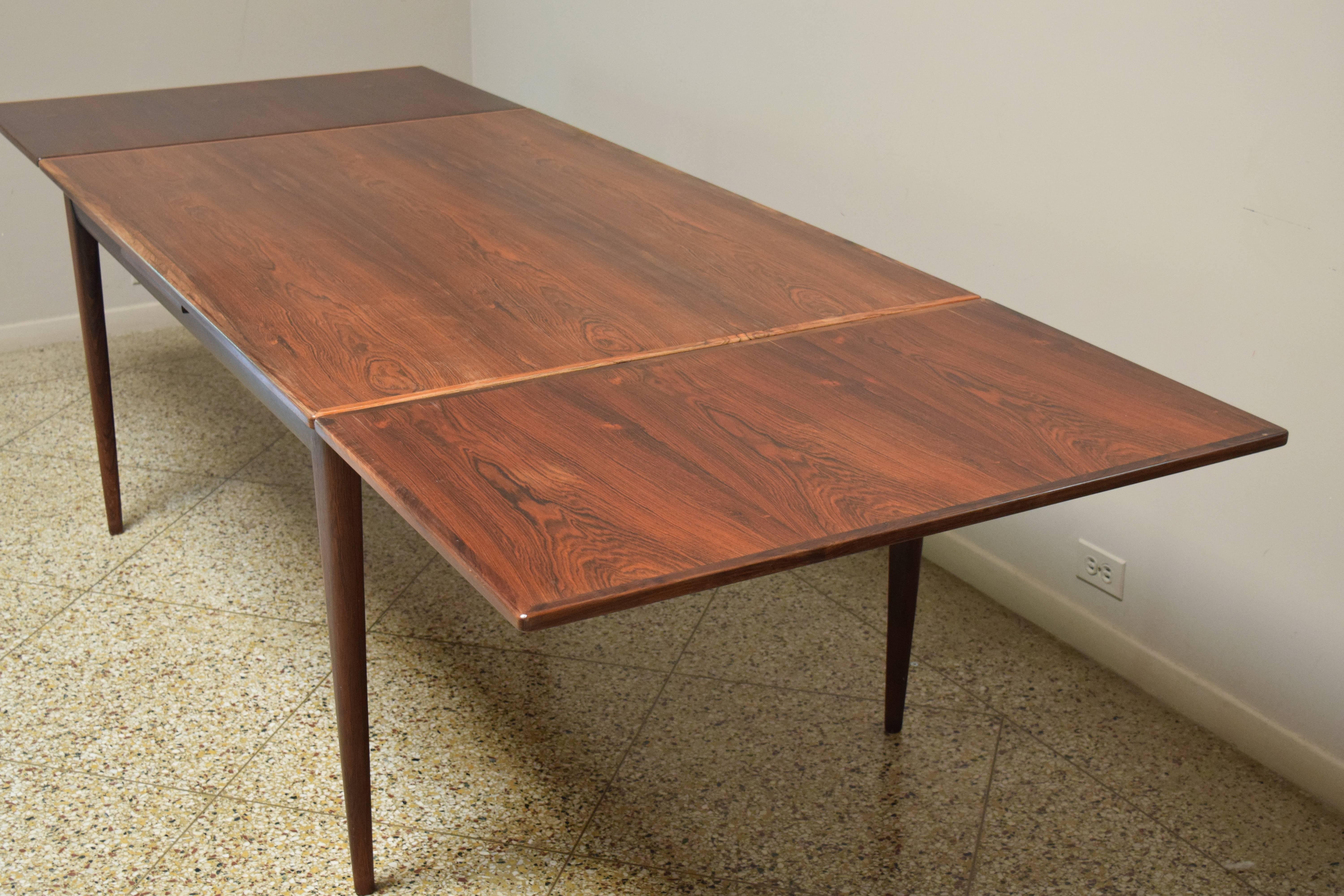 Beautiful model #12 dining table with tapered legs and self-storing leaves by Niels Otto Møller for J.L. Møller. Signed with manufacturer's sticker and Danish control sticker. Table measures 59" L closed; 104" L fully extended. Set of