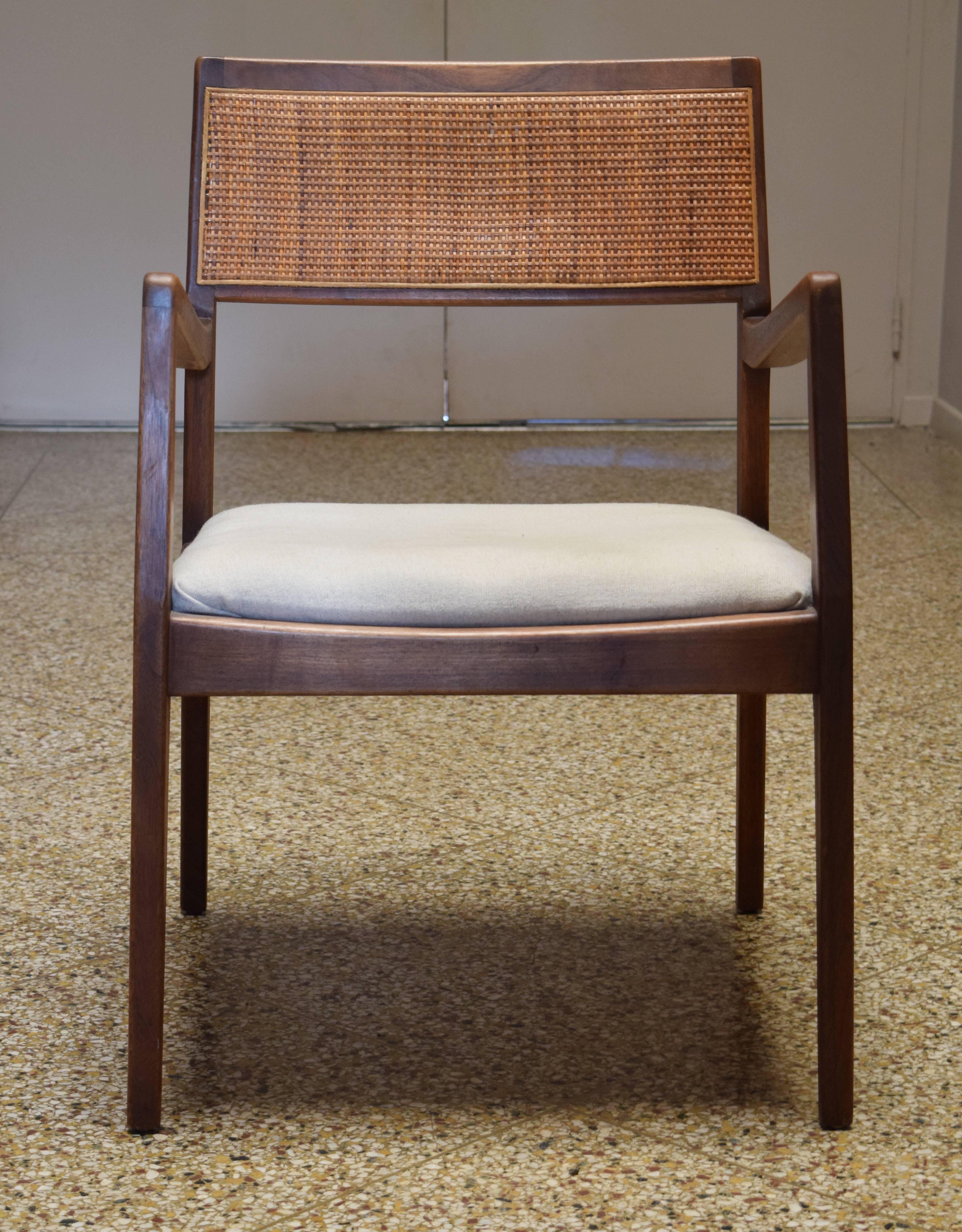 Sculpted walnut armchair with caned backrest by Jens Risom.