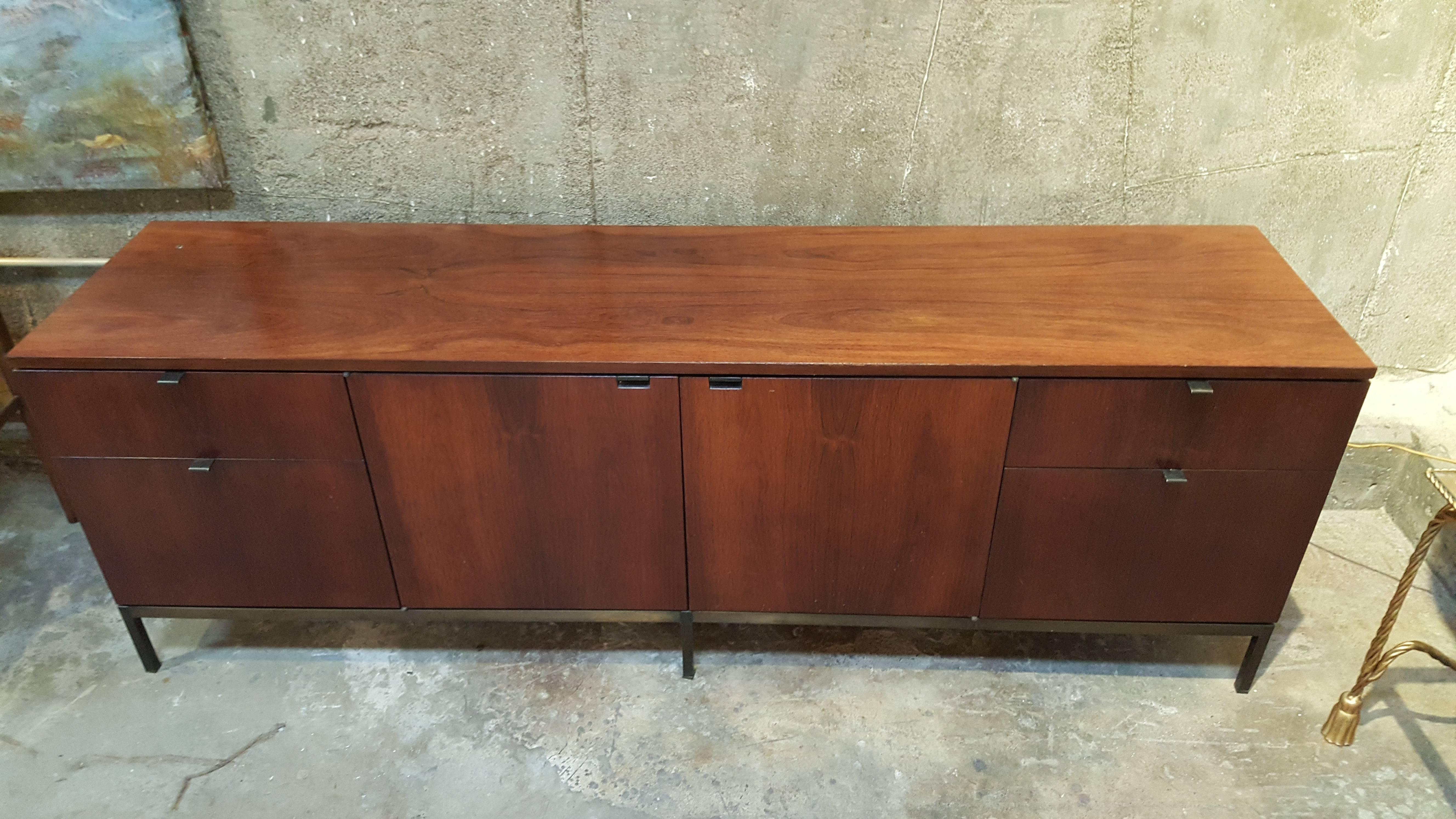 Rosewood credenza on bronzed metal base by Knoll International. Tab on upper left surface locks entire cabinet. Retains original Knoll label, original finish.