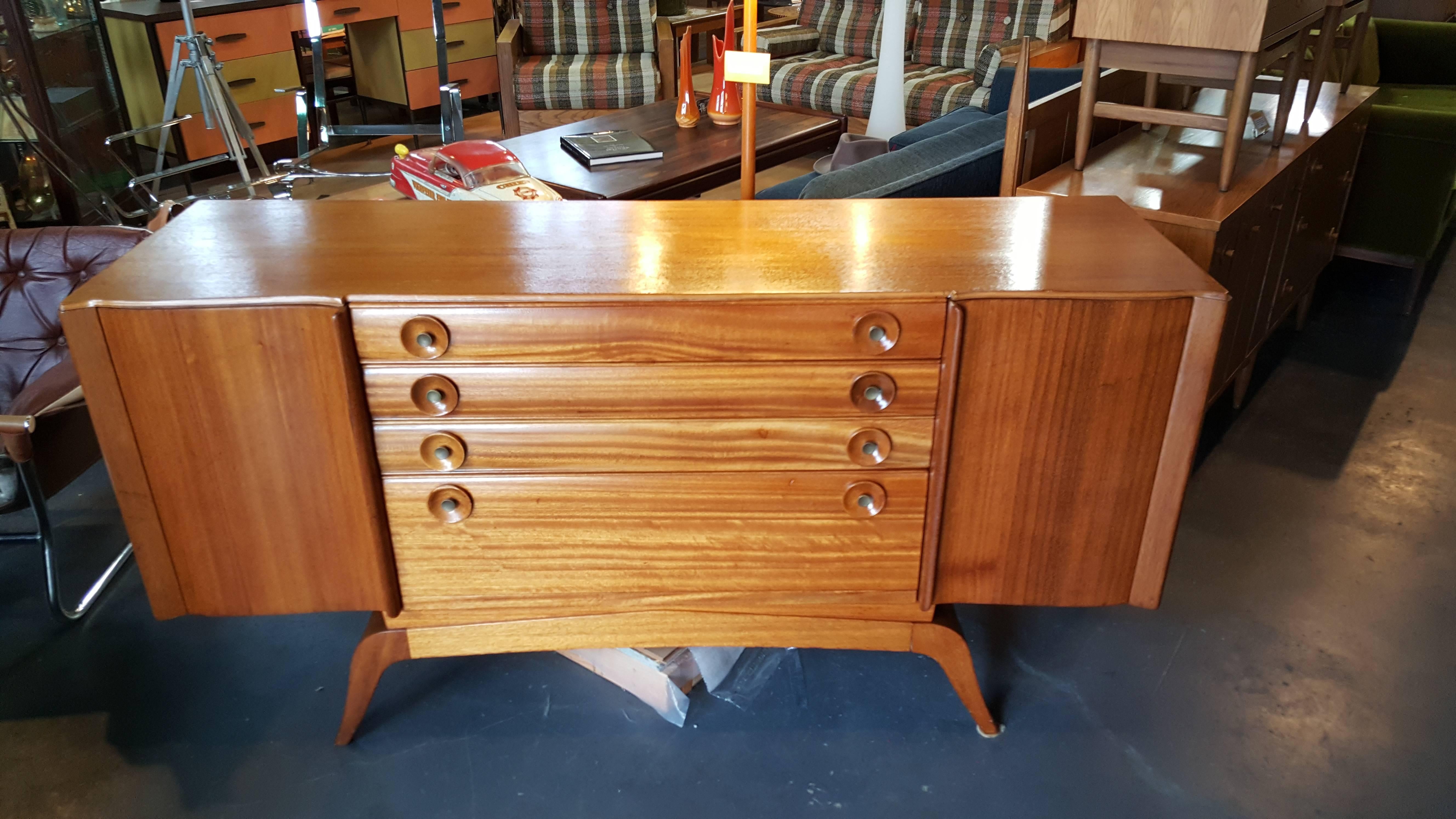 A beautiful golden mahogany credenza designed by Gilbert Rohde, circa 1942. Solid ribbon cut mahogany drawer and door fronts with a beautiful figured wood grain. Deep and rich glow to the original finish. Ample storage with drop-front bottom drawer.
