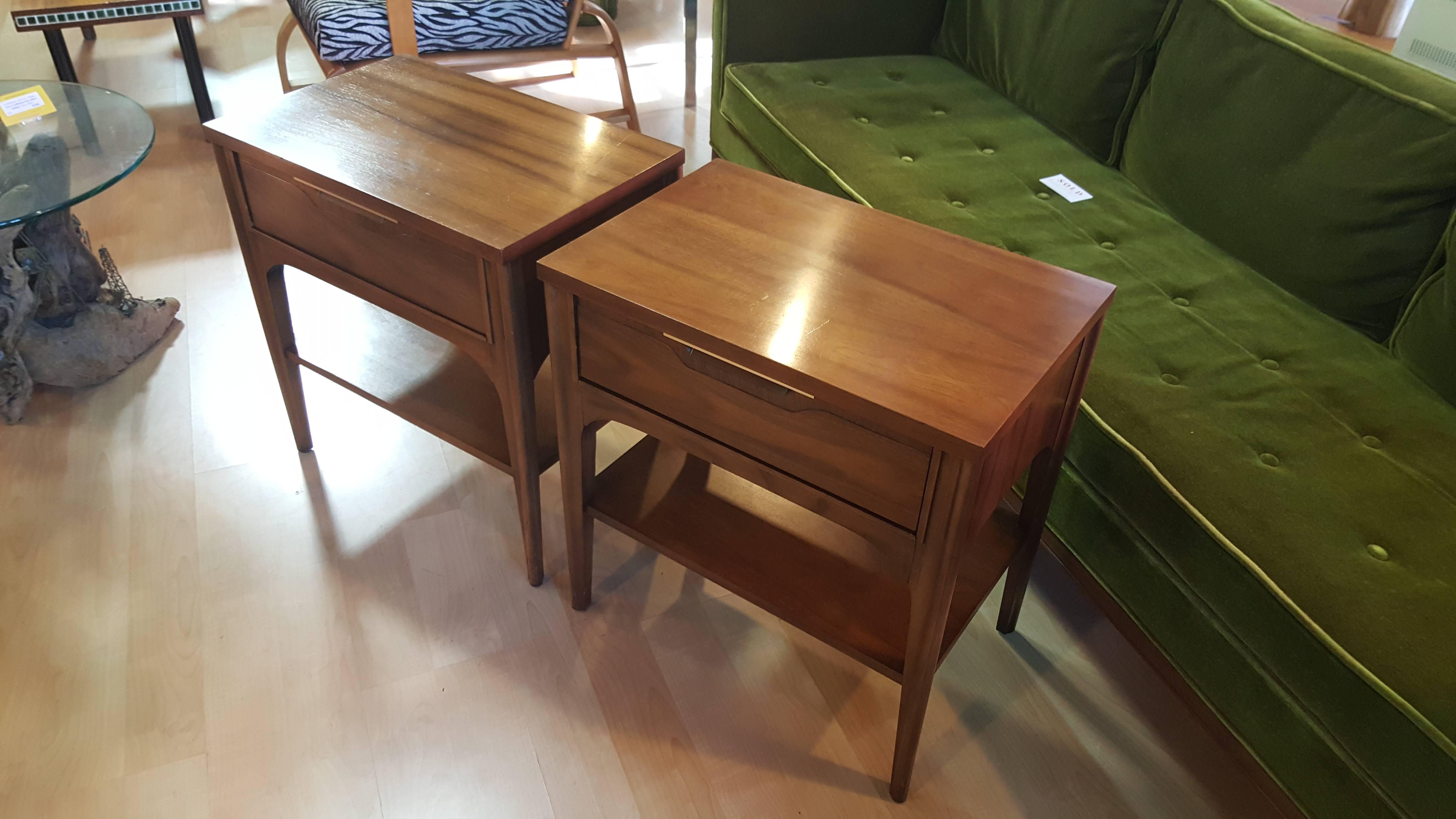 Fine materials and craftsmanship in these Mid-Century Modern walnut end tables by Kent Coffey. Solid oak secondary woods and dovetail construction. Nice original condition and finish. Each table features and single top drawer and magazine shelf.