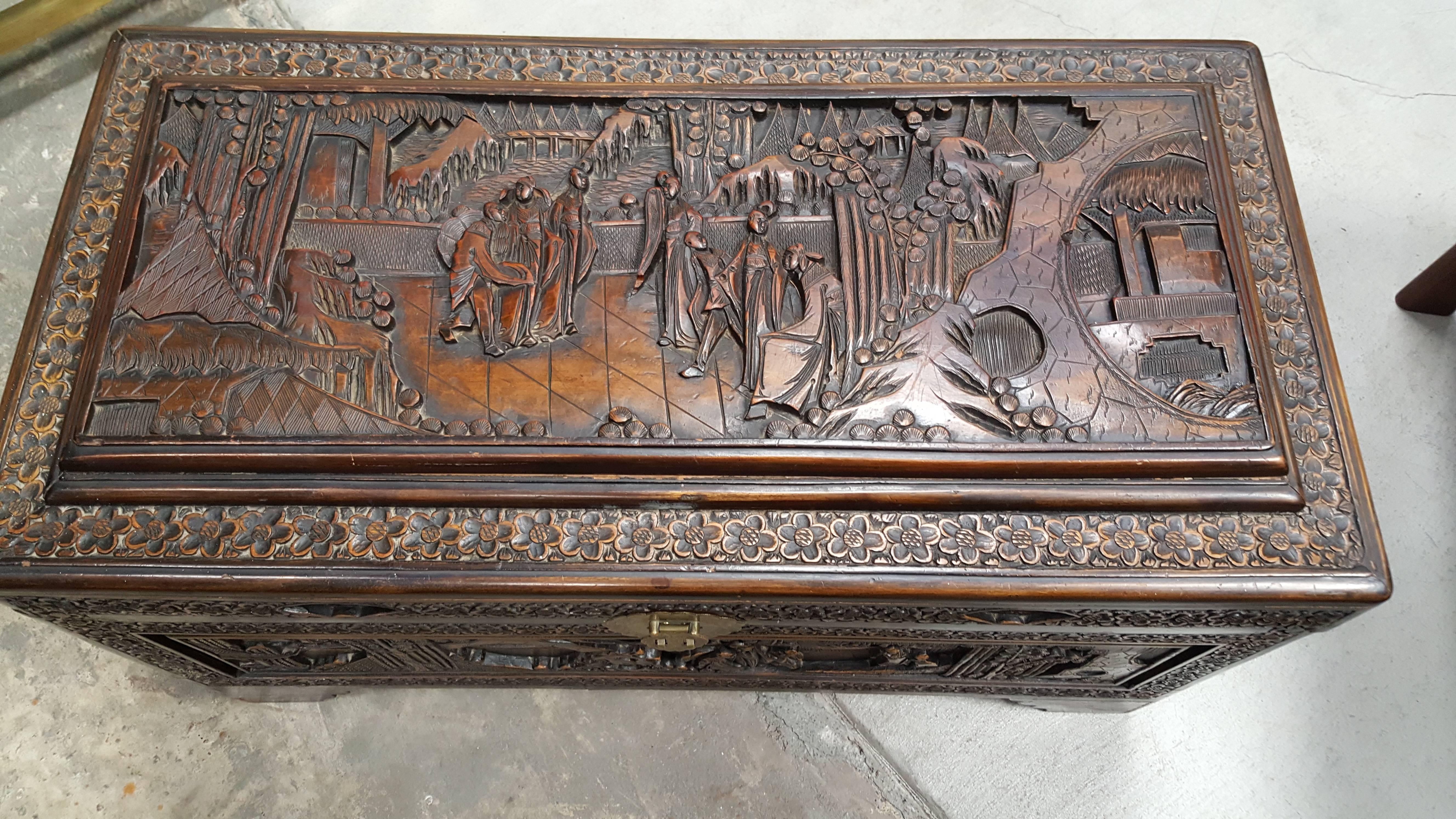 A mid-20th century high relief and hand-carved Chinese trunk. Brass mounts and camphor lined interior. Original finish. This trunk would make an excellent coffee or side table as it is carved on all sides.