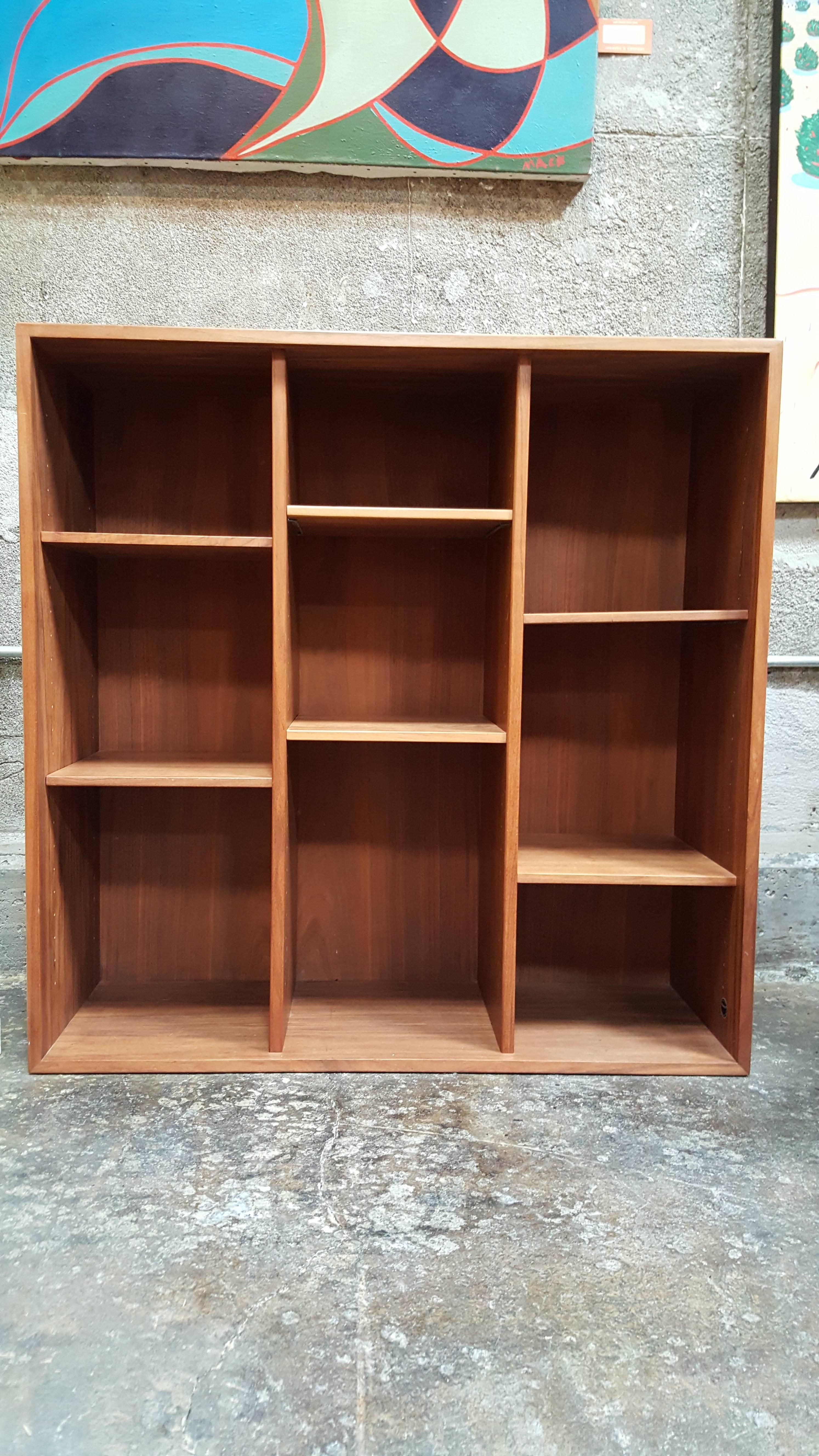 A teak shelf unit with adjustable shelves in the manner of Peter Hvidt. Notice areas of figured teak wood grain, nice glow to original finish. Retains Danish control label.