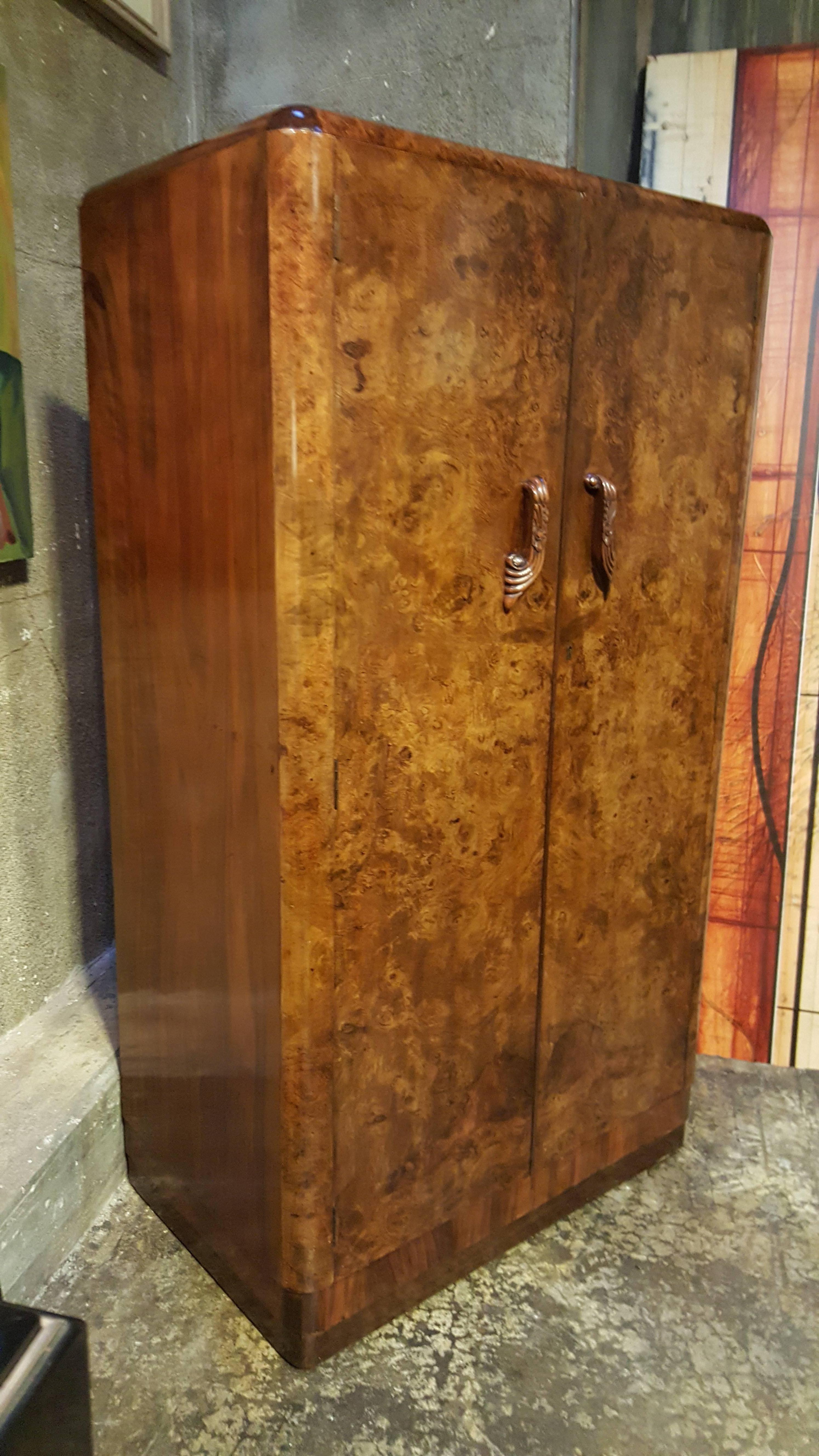 A compact size, fully fitted butlers / wardrobe cabinet in burl-walnut with Art Deco pulls. Interior features a shoe rack, clothes hanger, glass cabinets and shelving. The diminutive size will fit nicely where extra storage is needed. Perfect for a