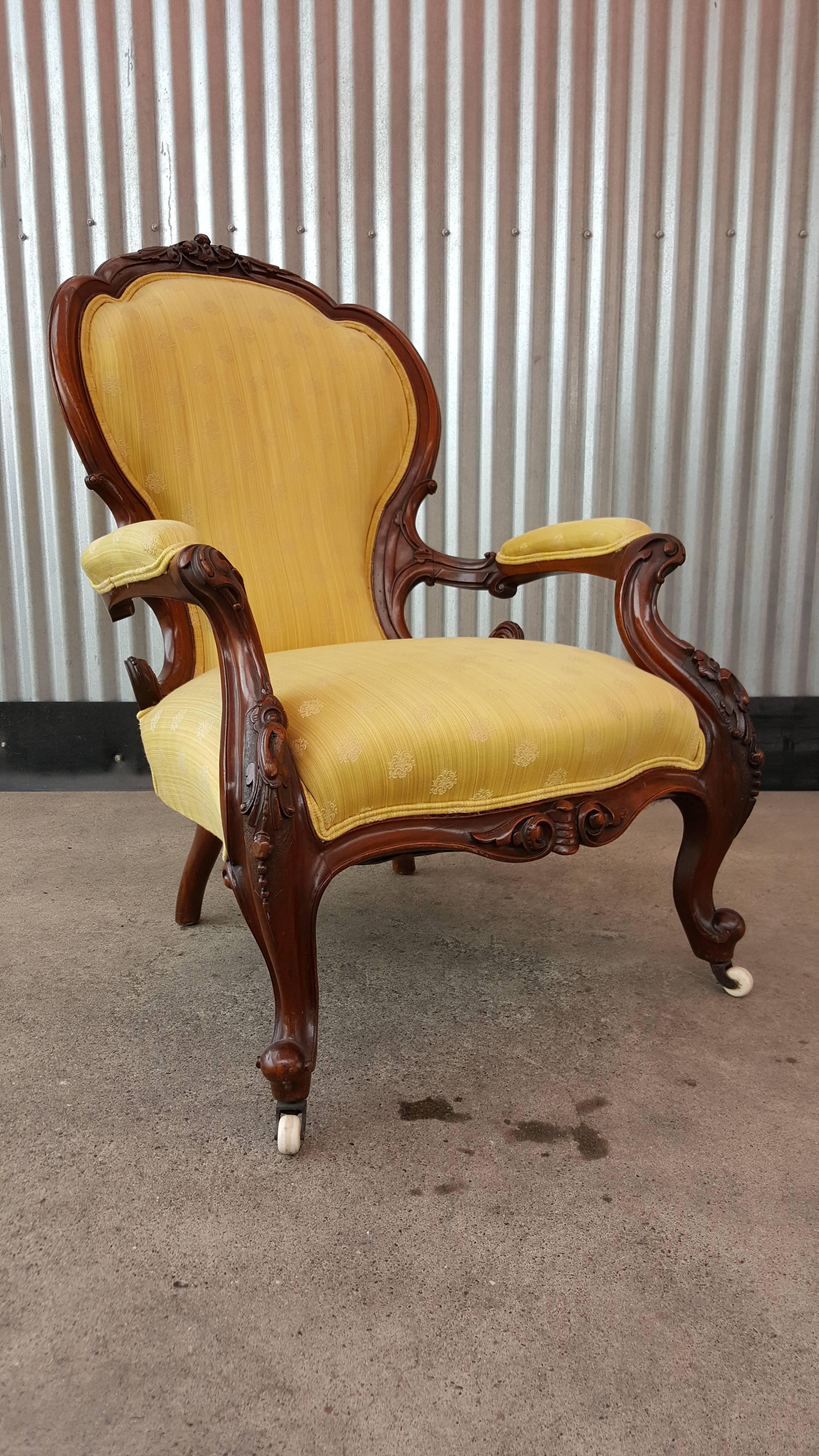 Fine craftsmanship and carved detail in this solid walnut armchair. Original porcelain casters. Beautiful patina and dramatic curves to solid walnut frame. Older re-upholstery is in good condition.