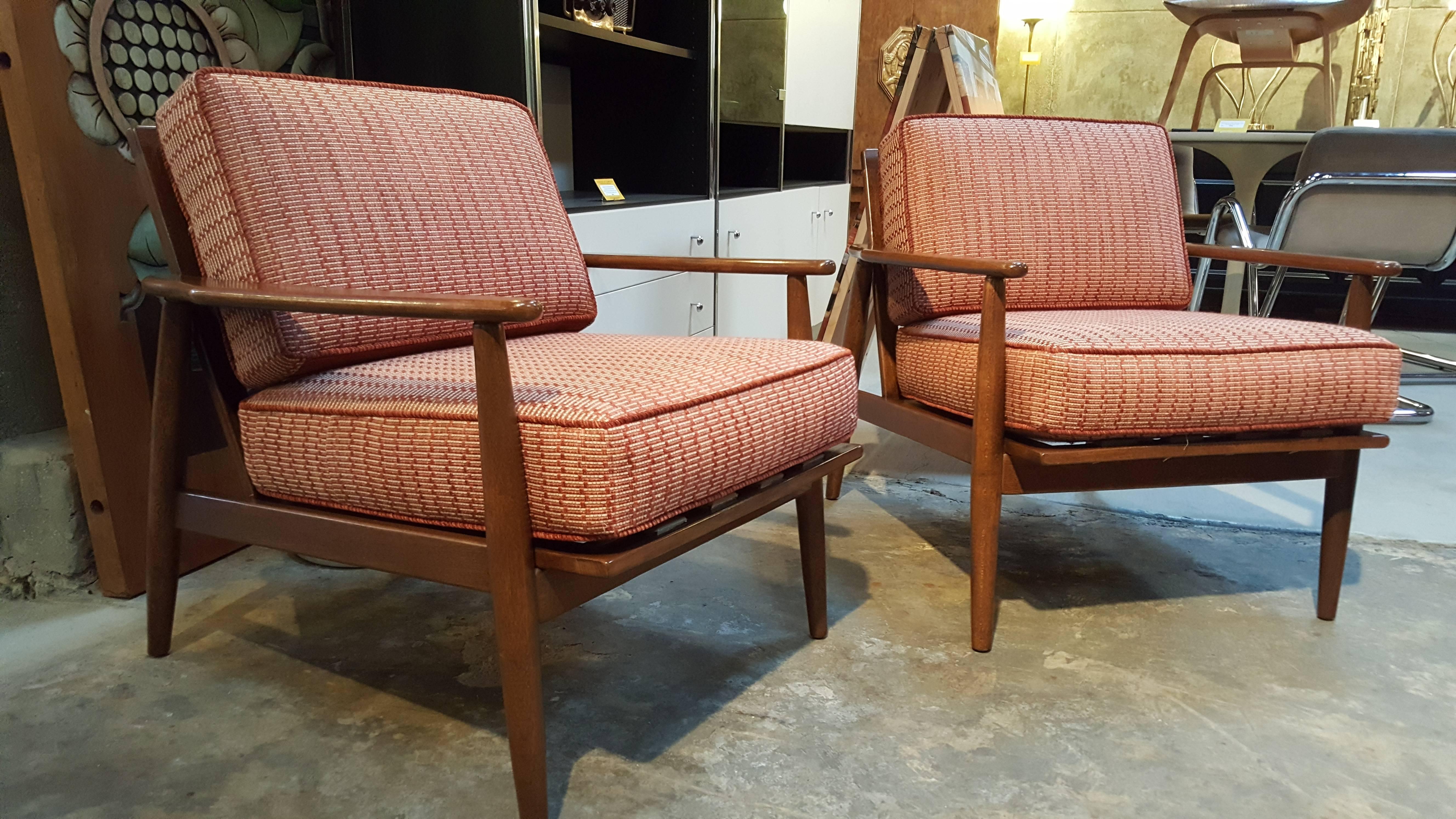 A pair of 1960s Danish modern style lounge chairs crafted in solid walnut by Baumritter Furniture, USA. Predecessor company to Ethan Allen Inc. Very nice original finish and condition to chair frames. Older re-upholstery with new foam in good