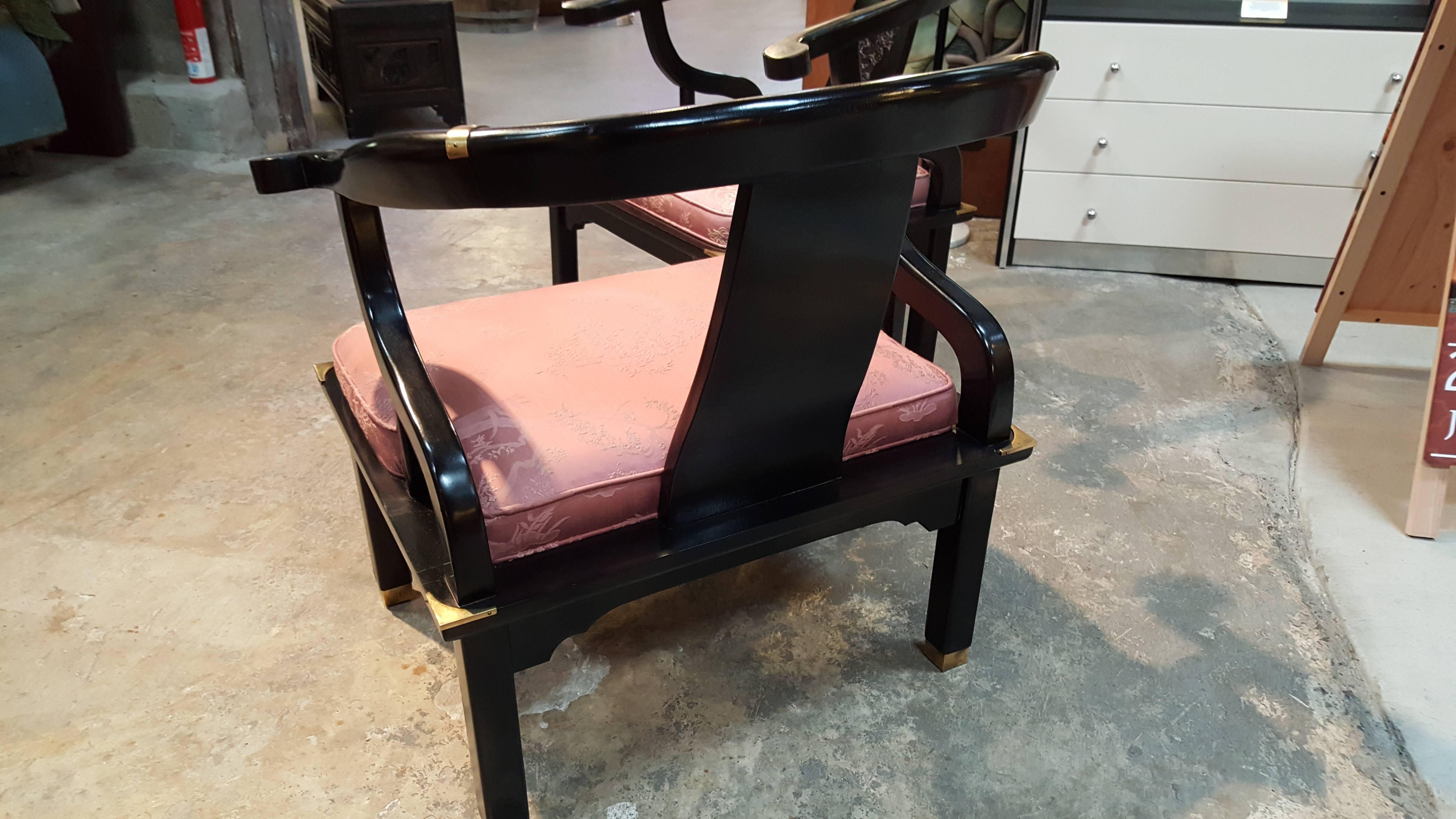 A striking pair of black lacquer Ming style lounge chairs with brass mounts. Similar to James Mont for century furniture. Quality workmanship, solid, sturdy chairs. Excellent original finish, replacement of original upholstery recommended.