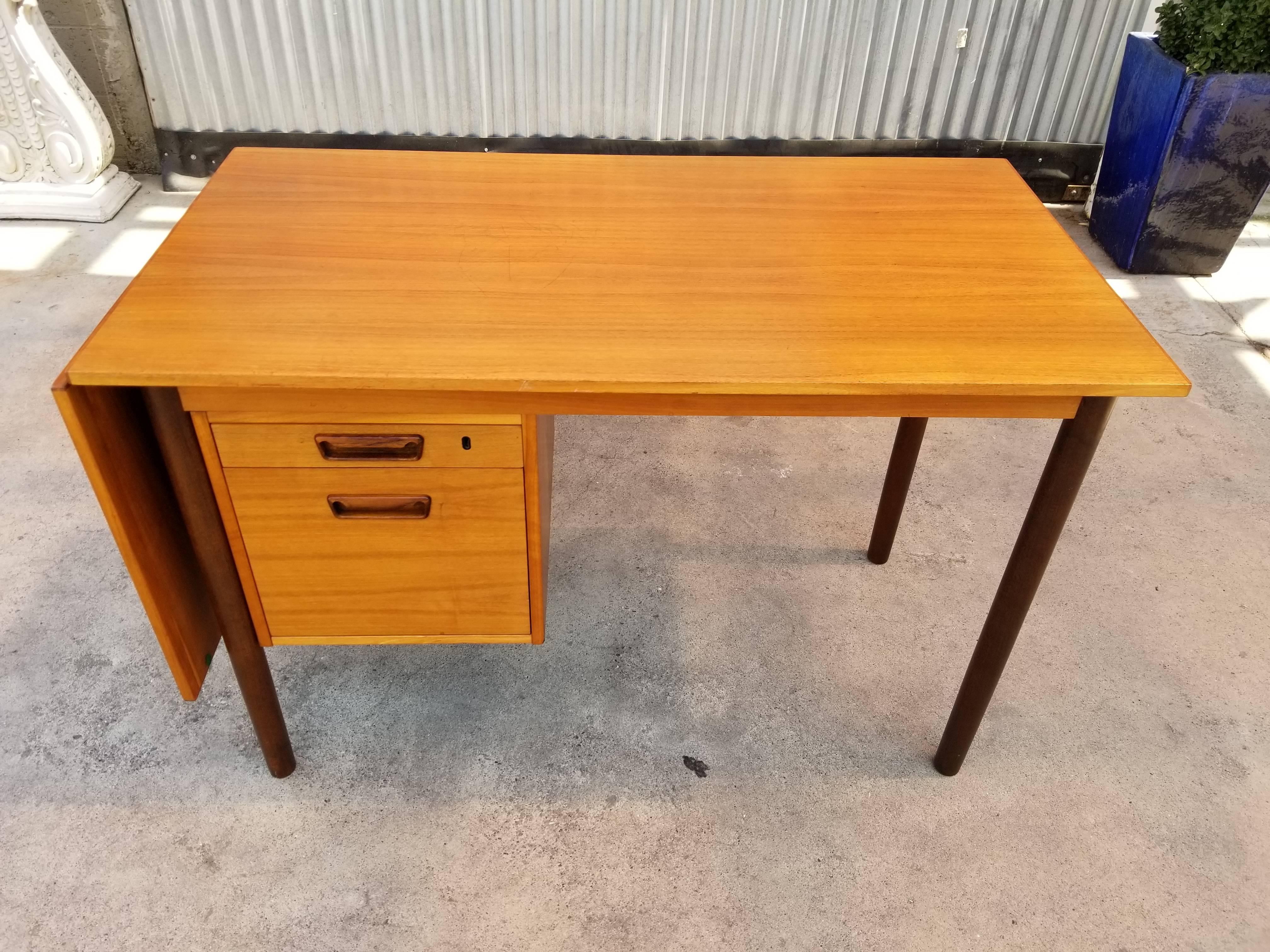 A Danish Modern teak drop-leaf desk designed by Are Vodder. Stamped on underside H. Sigh & Sons. Beautiful glow to finish with contrasting rosewood stained legs. Excellent original condition, all drawer glide smoothly, drop-leaf is sturdy, includes