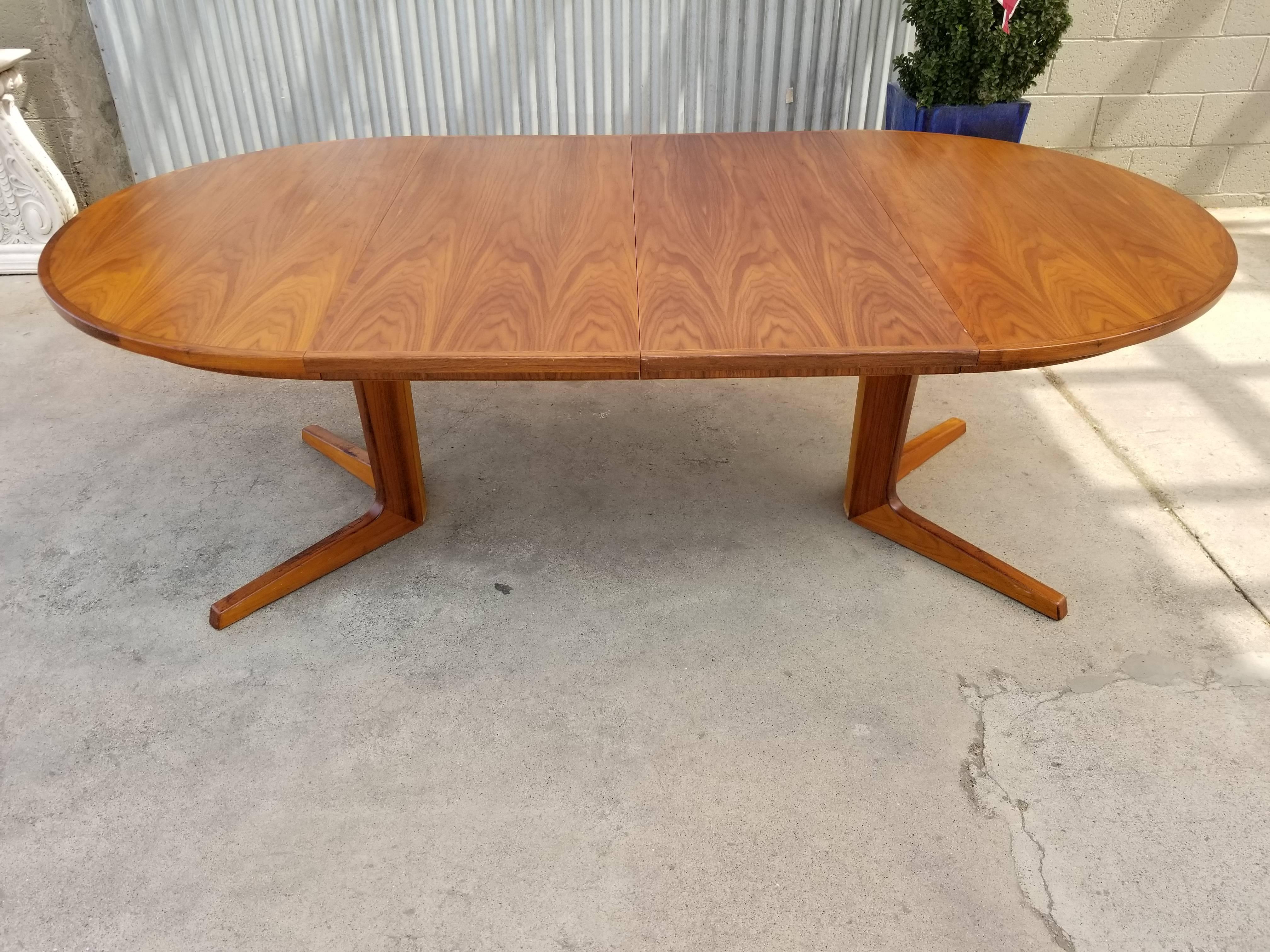 Teak Danish modern circular dining table. Includes two 20" table leaves expanding table to a maximum width of 87.75". Solid teak pedestal base and legs. Soft wood with teak veneer top. No particle board. Adjustable glides built into legs