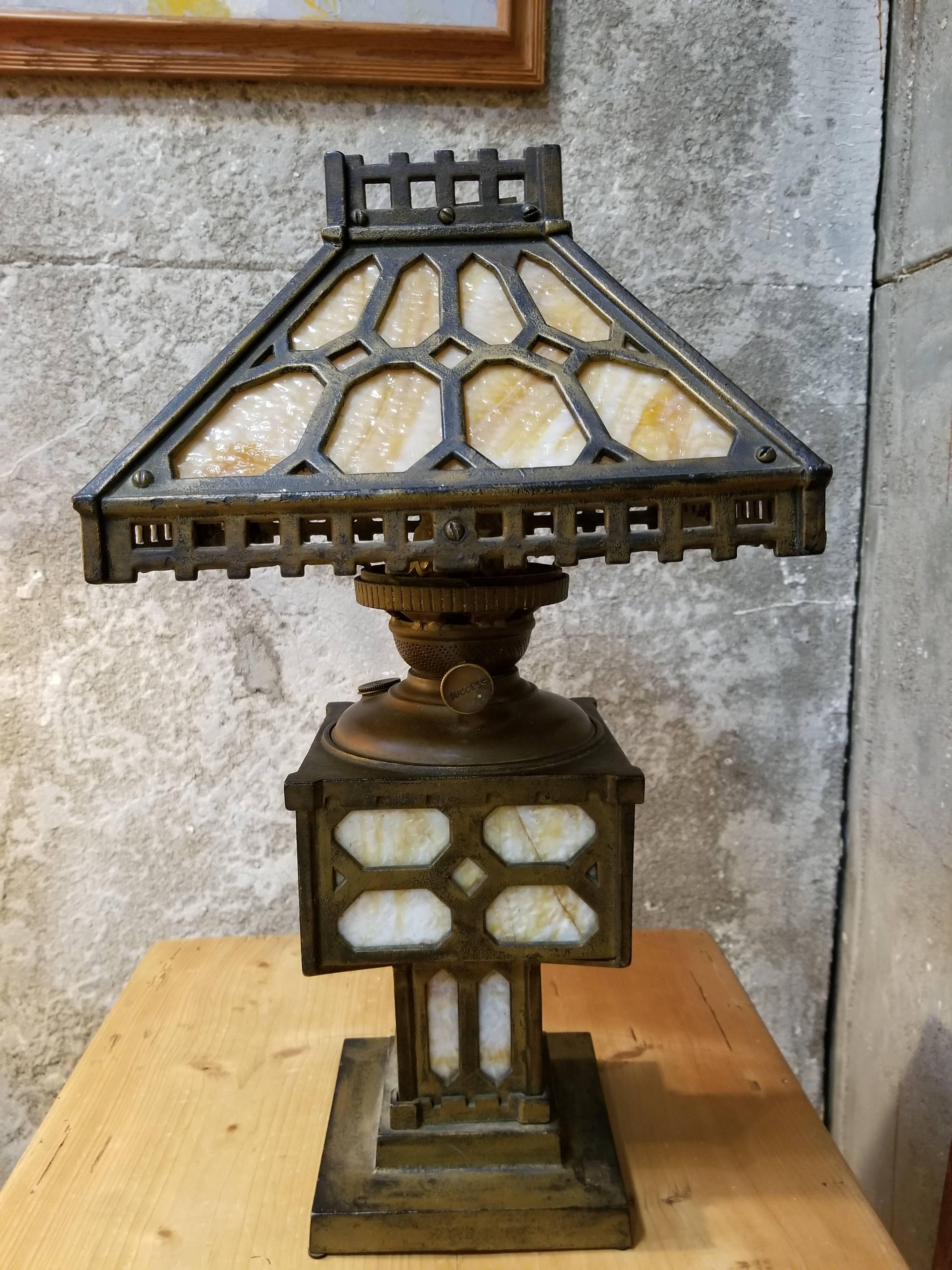Period Arts & Crafts opaque slag glass and iron table lamp, circa 1915. Beautiful patina to original finish on cast iron frame. Original brass oil burner intact, converted to electricity circa 1930s. Several cracks to original glass panels in lower