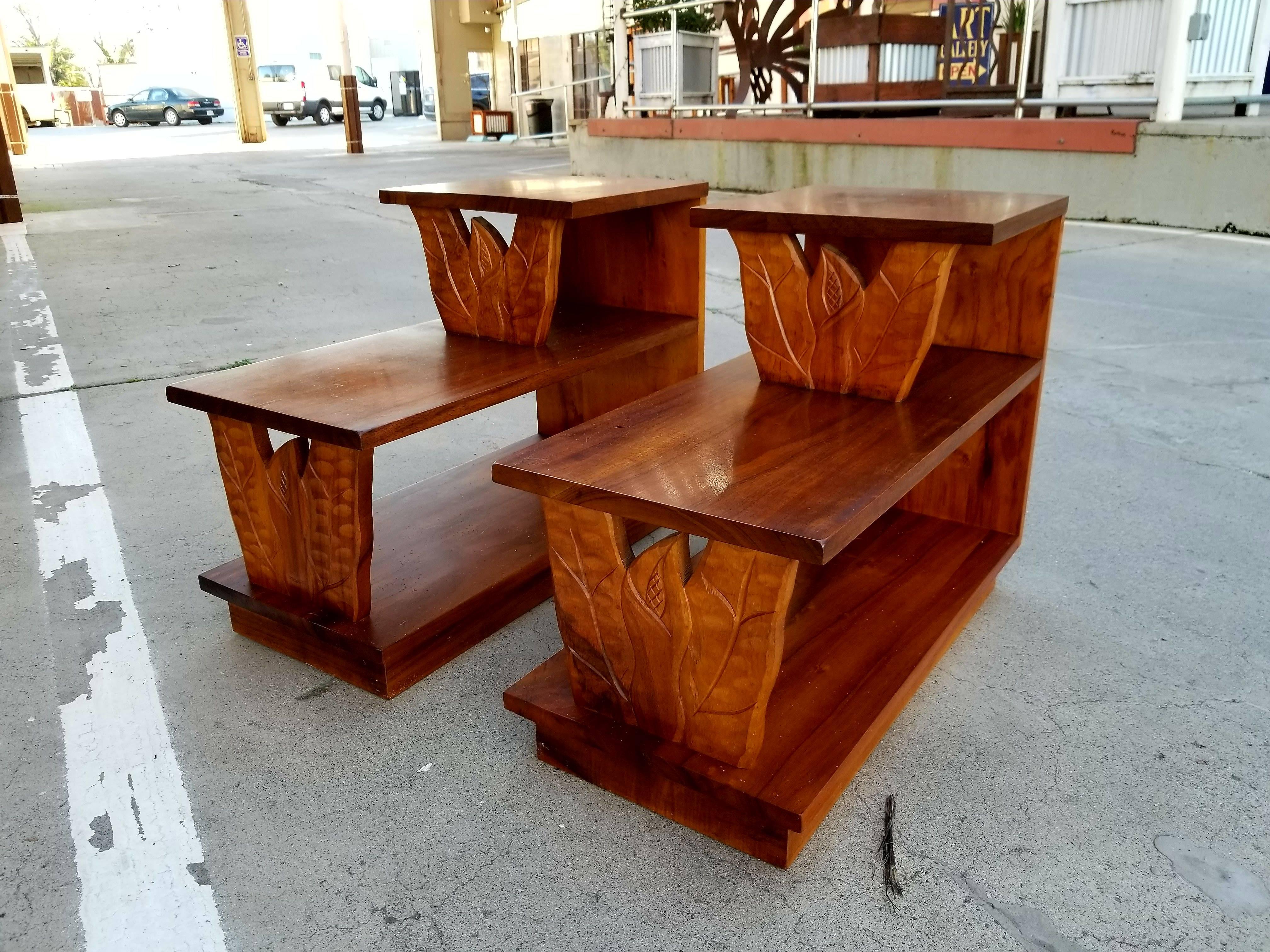 Exceptional and rare pair of Hawaiian Koa step-end tables from the 1960s. Made of solid Koa and curly koa. Warm glow to original finish. Carved leaf and anthurium floral detail. Beautiful figured wood grain. Classic Hawaiiana.