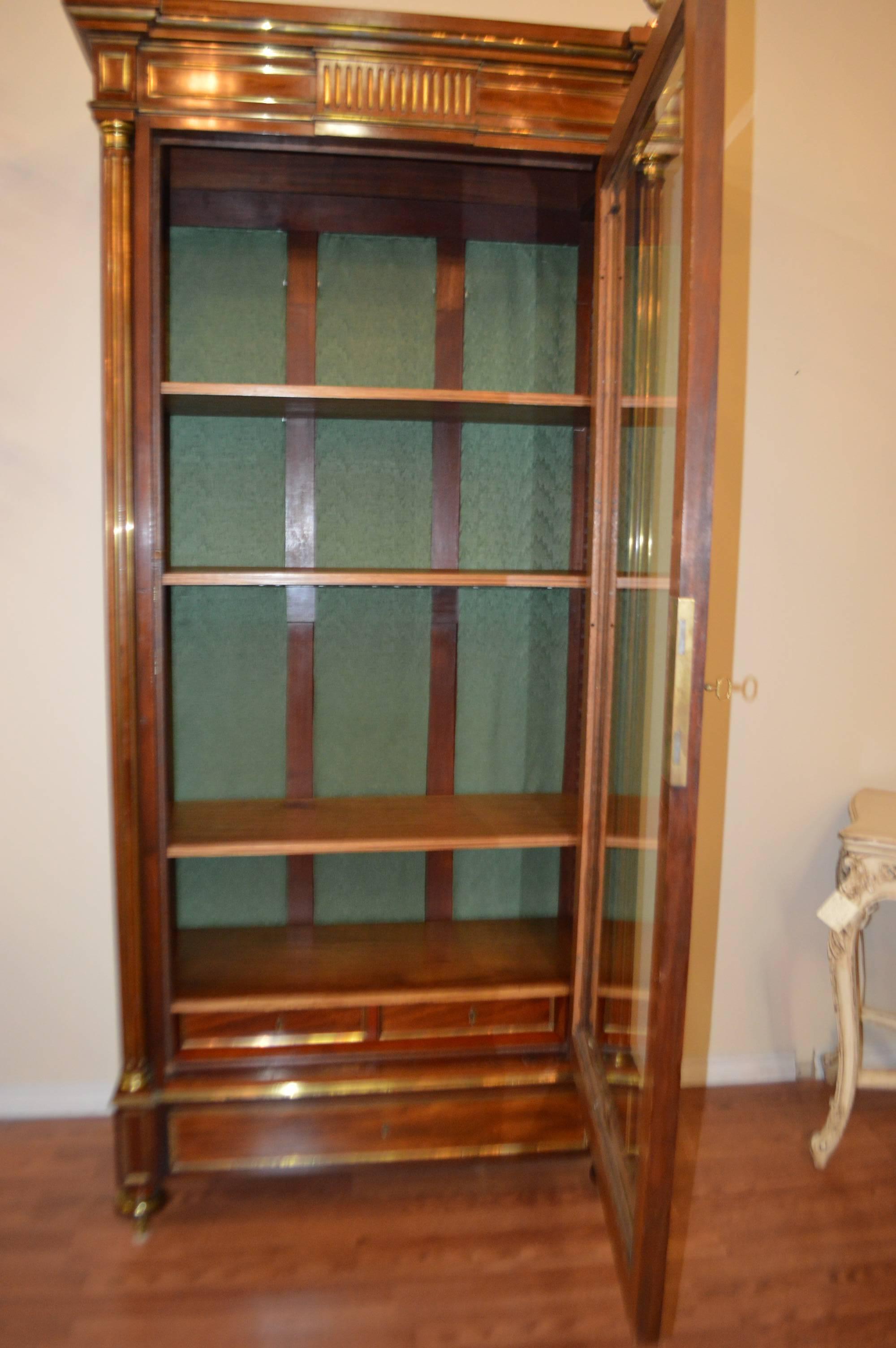 19th century Directoire style and fine quality mahogany bookcase with bronze molding. Unusual large bronze finials adorned the top of the bookcase.
The bookcase has also two drawers inside below the lower shelf and one outside. The glass door is