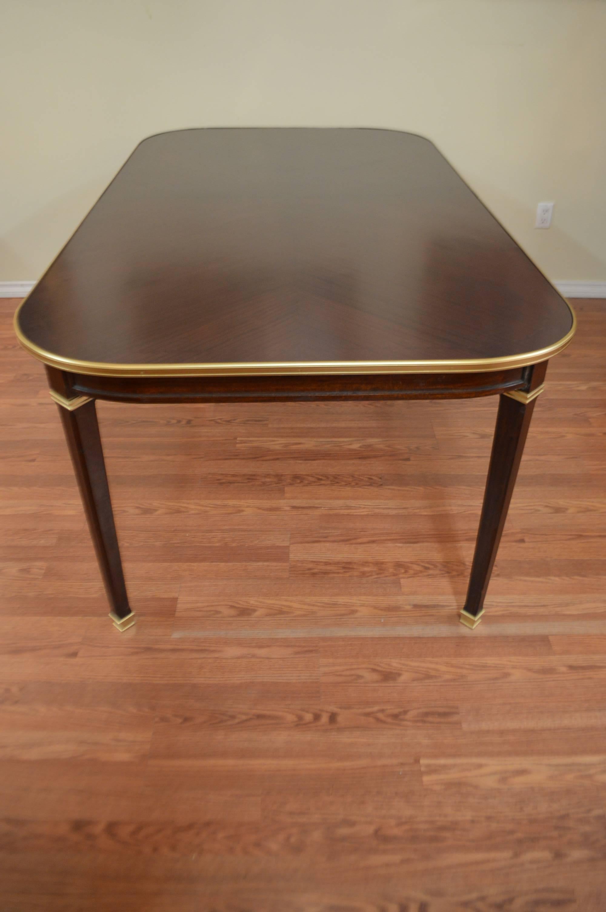 Elegant Directoire style walnut dining table, the inlay pattern top has been expertly refinished. There are gilded bronze molding around the edge of the table as well as the legs and the sabots.
