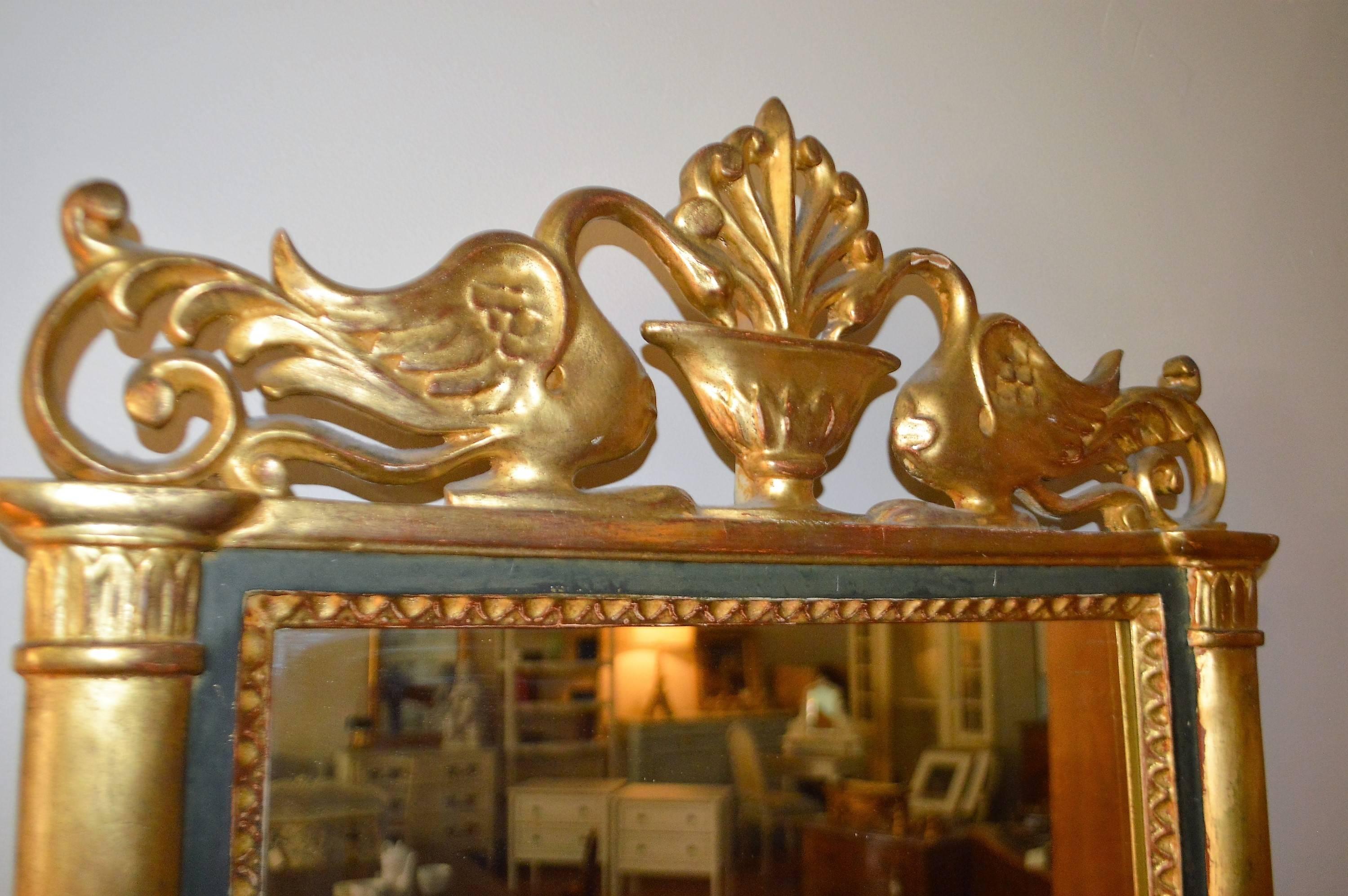 Unusual and highly decorative wooden gilded mirror flanked by two swans 
at the top and fleur de lis decor on the side panels. Dark green paint between moldings.
 