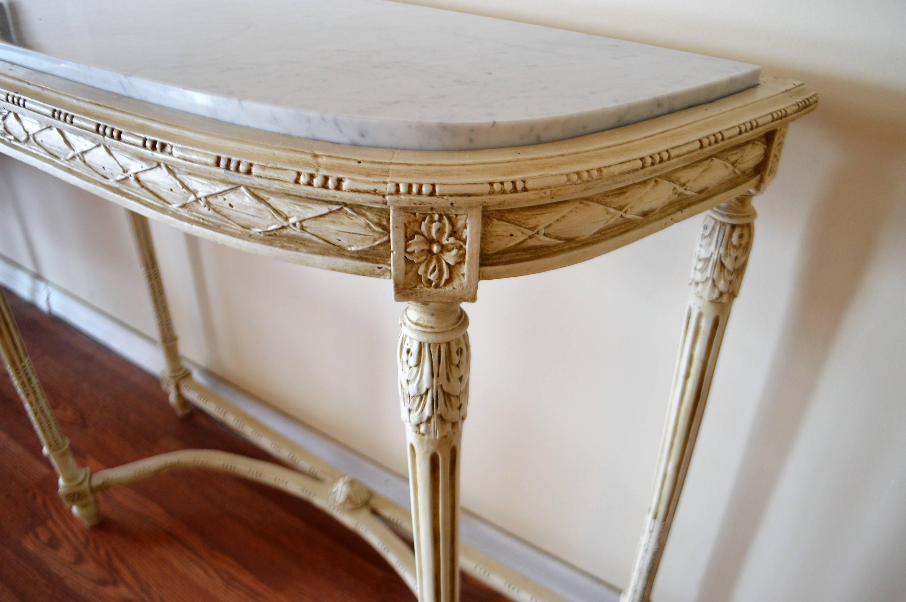 Louis XVI style console table, was painted in a cream tone over mahogany. The Carrara marble top is new. It has lovely hand-carved details on the apron as well as the legs. The entretoise that joins the legs is attractive as well as
giving