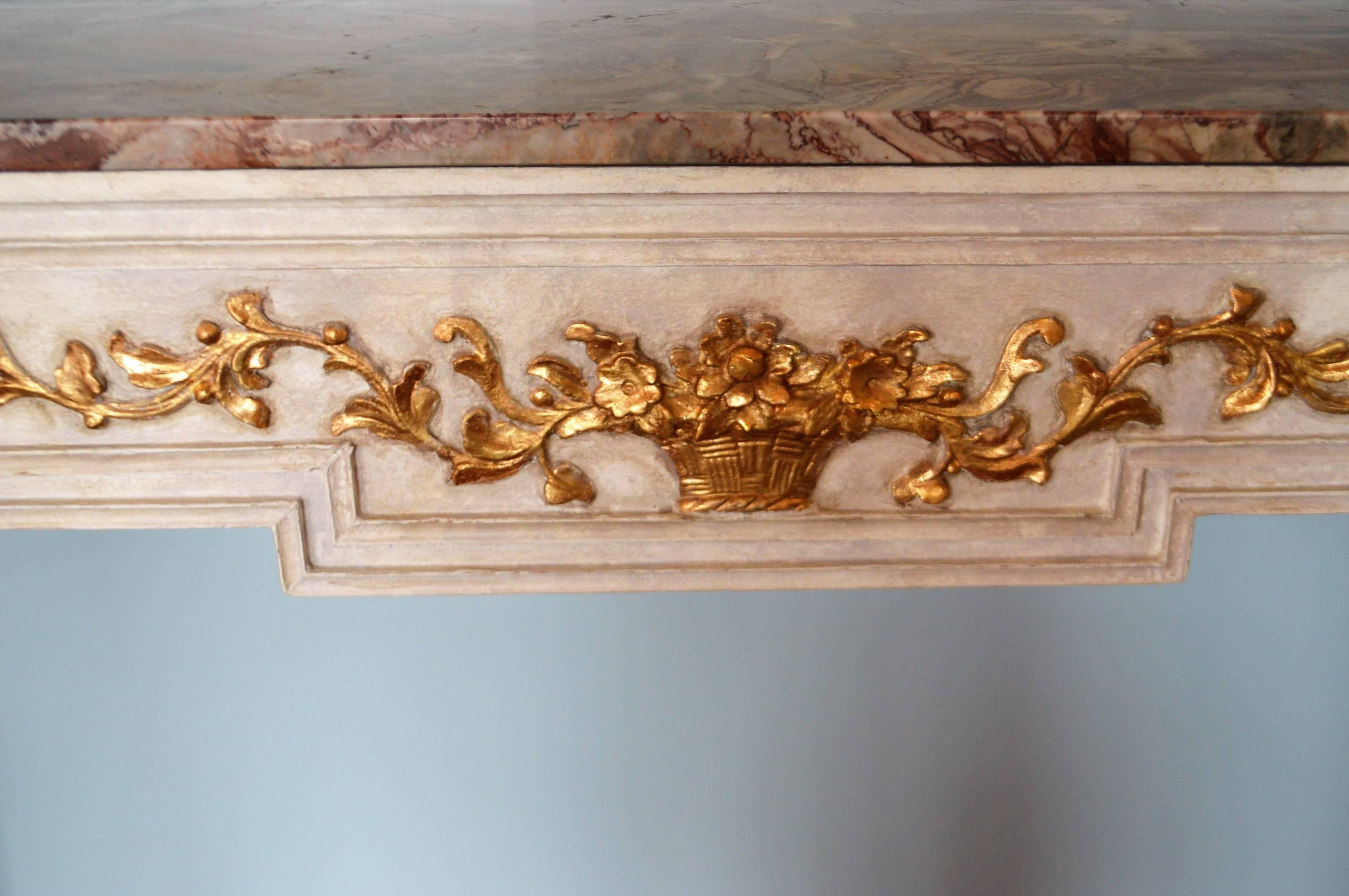 Unusual stone like custom paint finish on this exquisite Louis XVI style console. The front has elegant hand-carved details representing a basket, flowers and acanthus leaves all done in gold leaf. The marble top is very attractive in tone of brown