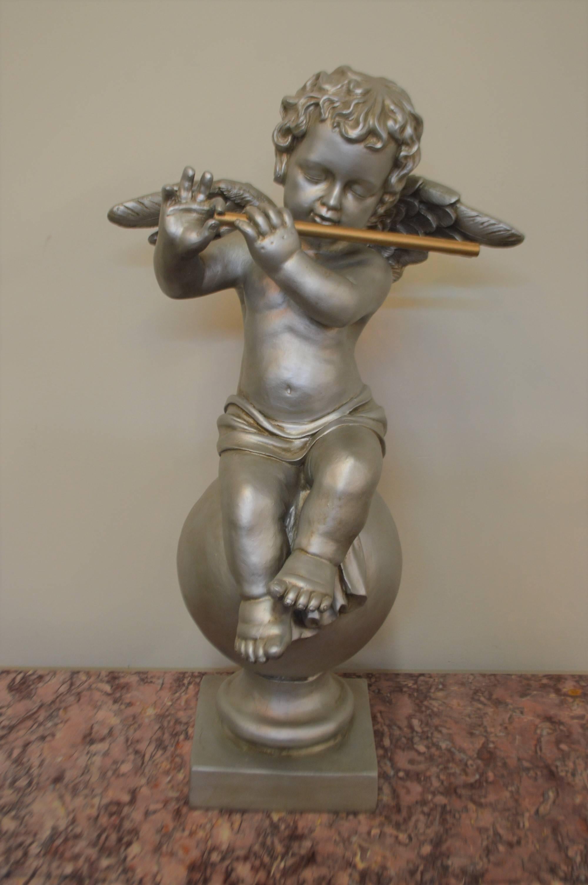 Unusual and attractive silver finished cherub sculptures. One holding a flute and holding a violin. The instruments are finished in gold.
