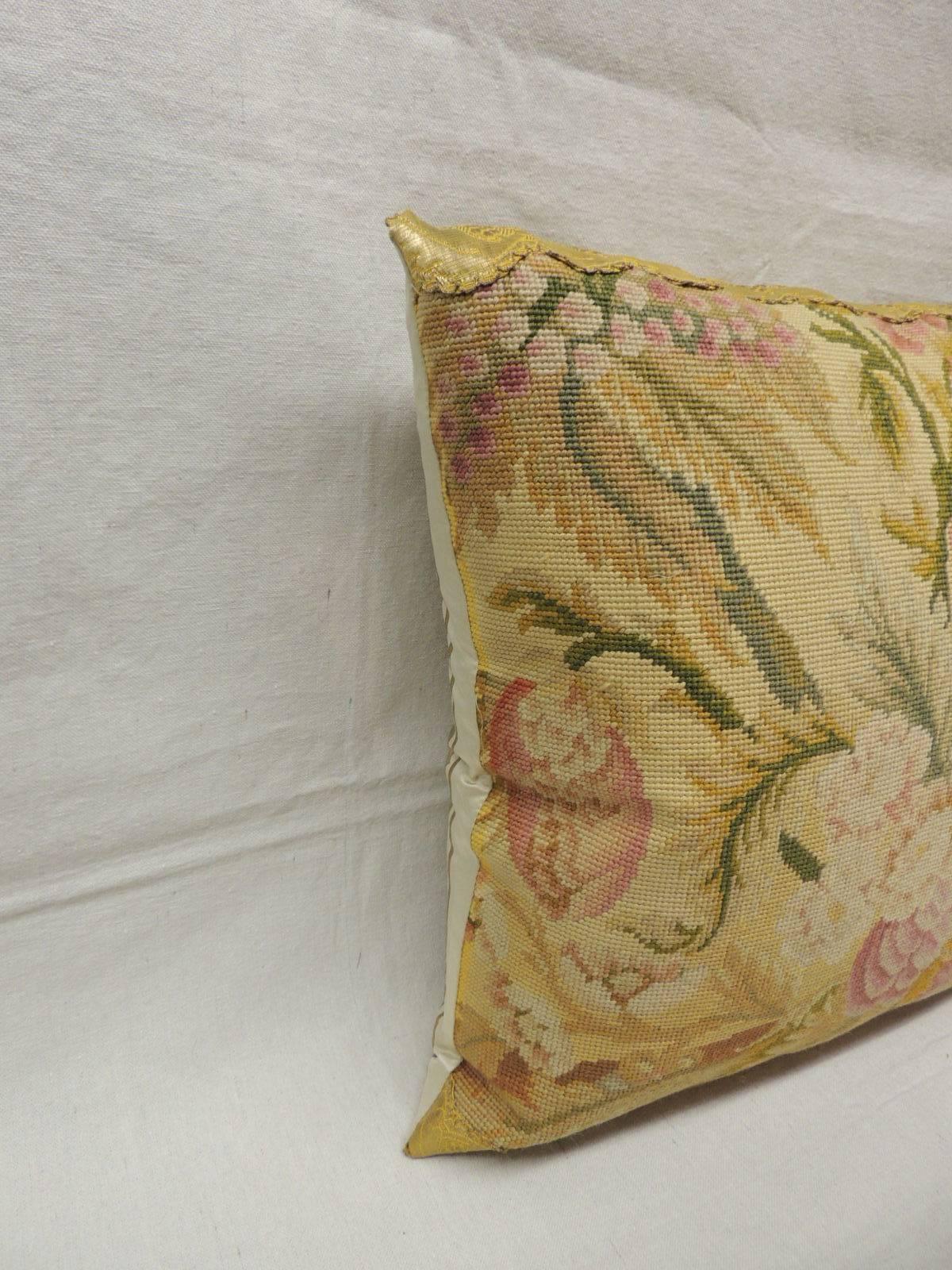Pair of 19th century tapestry pillows. 
Pair of floral tapestry pillows depicting a bouquet of flowers in bloom embellished with a 19th century metallic gold floral trim and a striped yellow silk backing. Textile panel is in shades of pink, fuchsia,