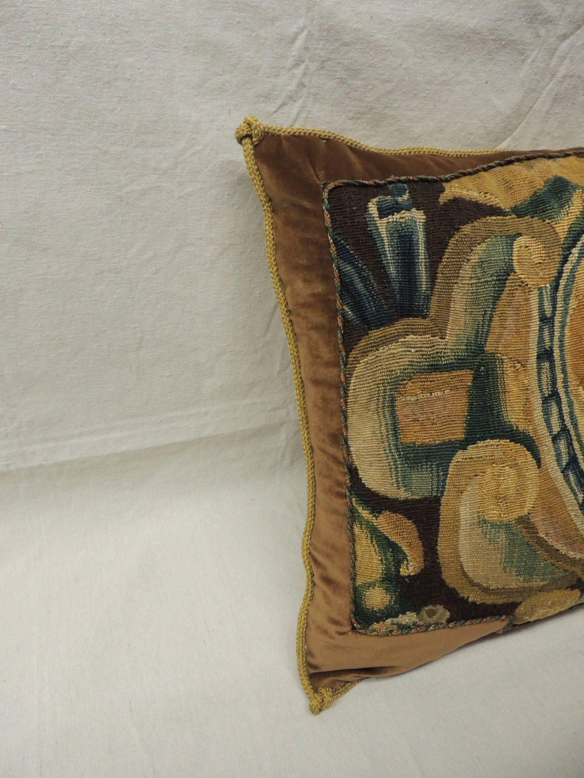 18th C. Verdure tapestry pillow with silk velvet frame accentuated with custom twisted silk cords in shades of orange, gold and green.  Antique metallic rope trim all around and yellow silk backing.    
Antique tapestry depicts flowers and fruits in