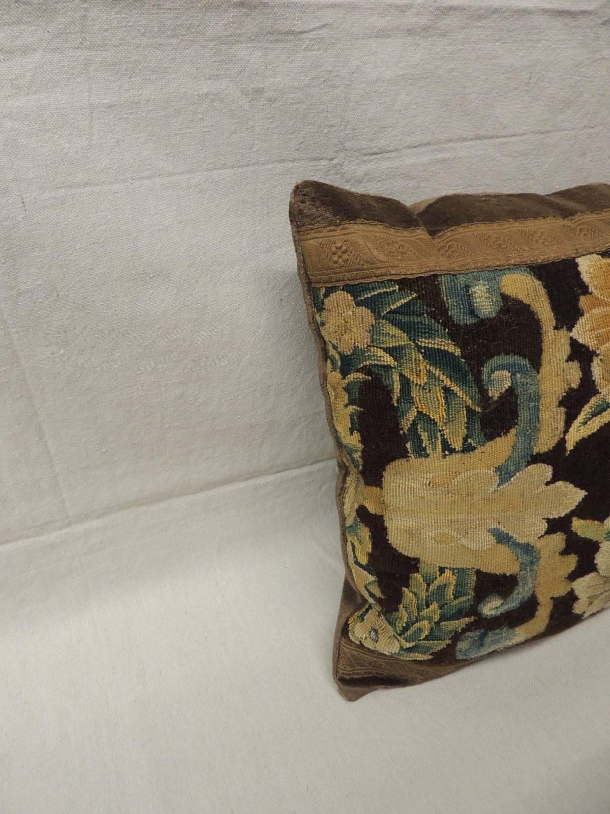 18th century Flemish tapestry bolster pillow with a classic floral design in shades of green, gold, hunted green and blue on a brown background.
Tapestry is accentuated with an antique metallic trim. Brown velvet frame and backing. Size: 29 x 18 x