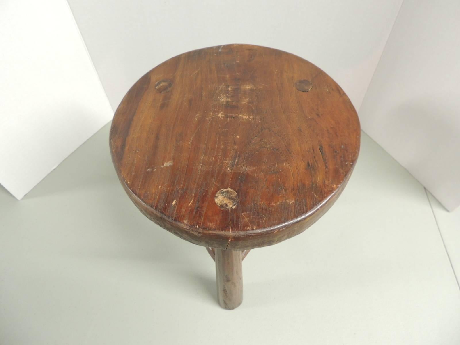 Round wood tripod three-legged low stool. Great side table for slipper chairs, drinks table or telephone table. Original manufacture brass plate under the top.