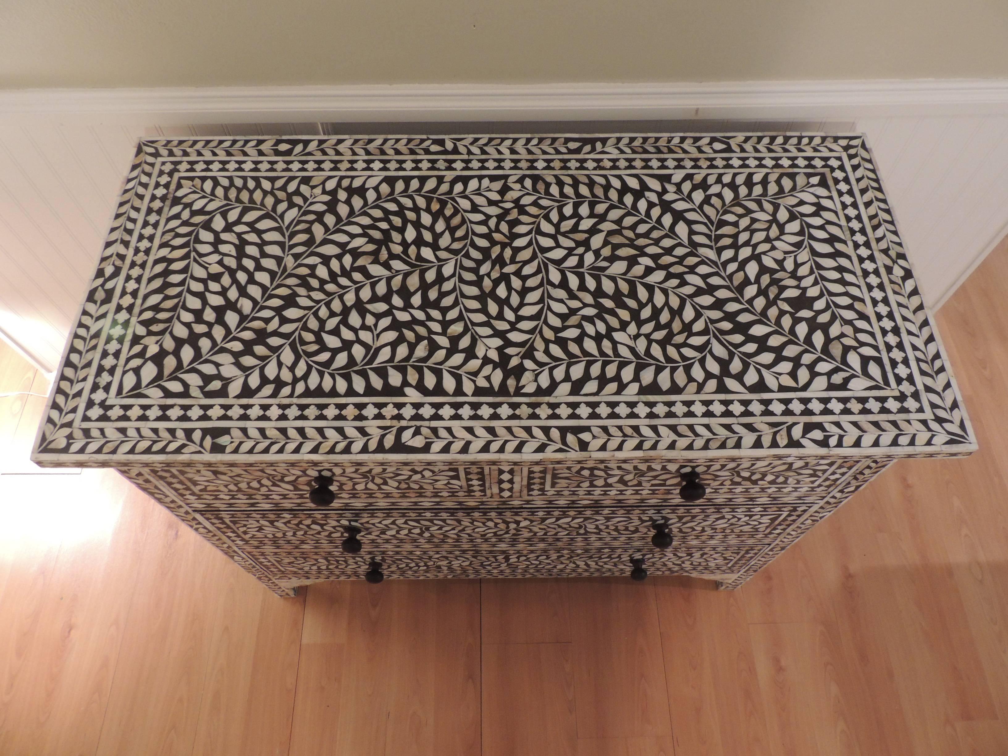Vintage black and white mother-of-pearl tall dresser. Traditional Syrian hand-inlaid technique, creates an undulating vine design on the top and drawers. Four sliding deep drawers, accentuated with ebonized wood knobs. The inside of the drawers are