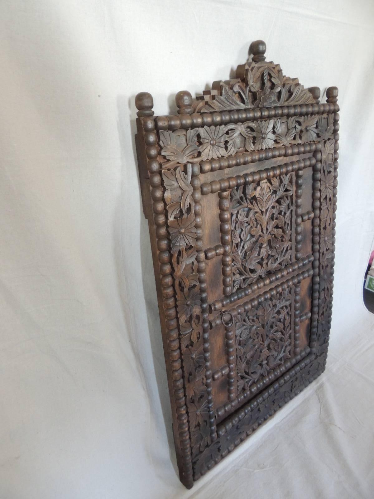 Large antique Indonesian hand-carved window. Teakwood dark stained. The window inset has a pierced carving relief of hand-carved flowers. Looks like it was the upper part of door. The inset window open with hinges to the inside. There is a small