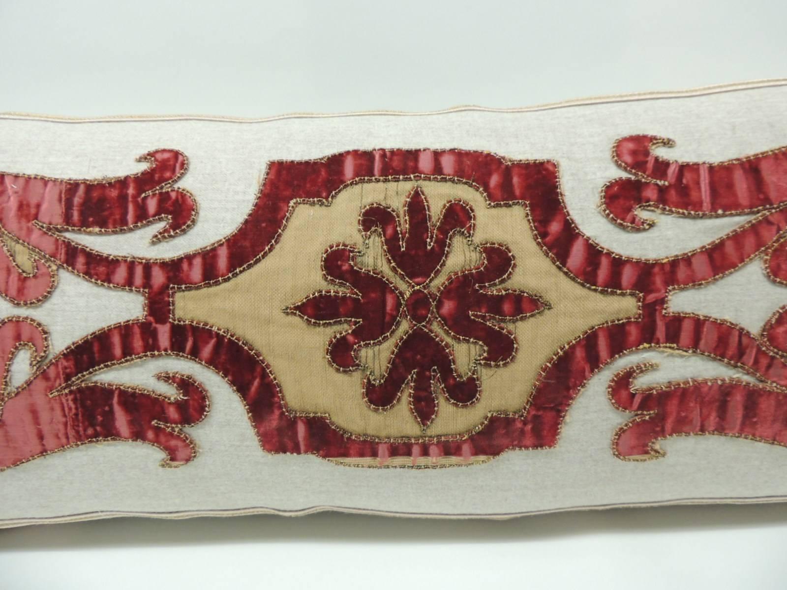 Bolster pillow made with a Byzantine style red cut velvet scrolling applique hand-stitched on vintage tan wool. The cut appliqué is a 19th century Italian piece and it was embellished with a gold antique metallic trim. The front panel with the