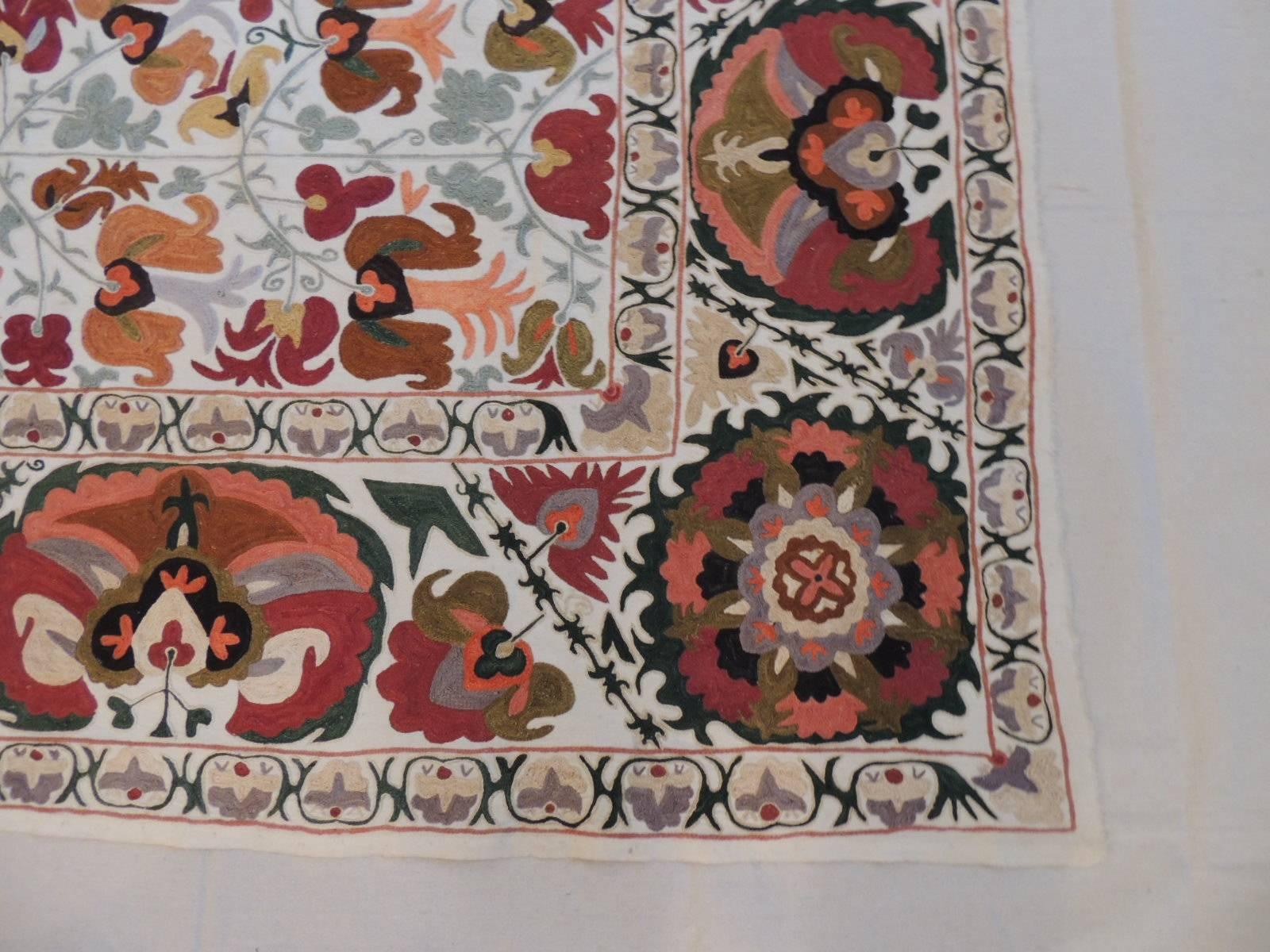 Offered by the Antique Textiles Galleries:
Vintage Uzbekistan embroidery Suzani textile panel. A needle work one-of-a-kind colorful traditional Uzbek Suzani floral textile. In shades of orange, red, green, beige and yellow with a border all around.