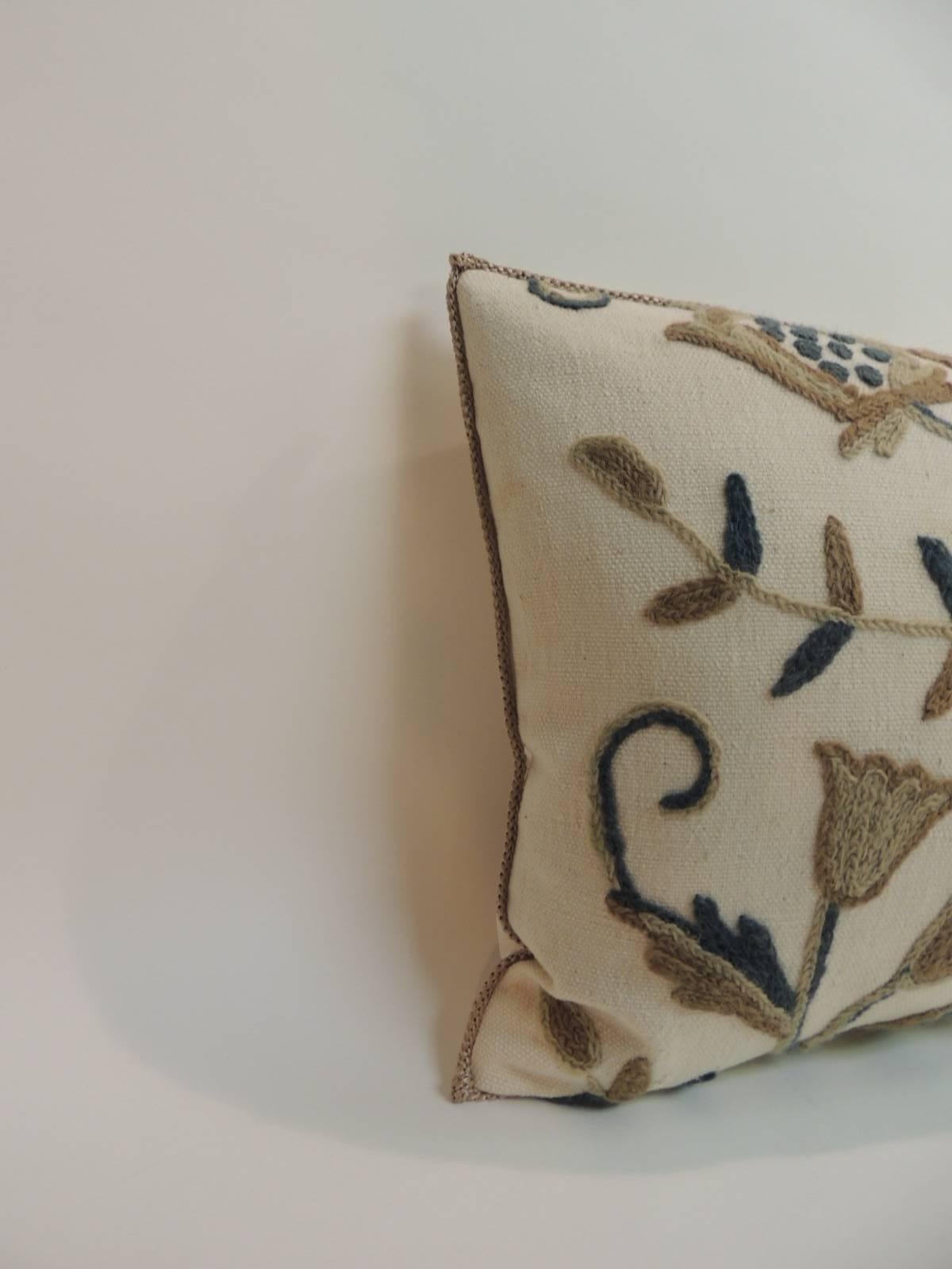 Floral pattern of wool embroidery on textured linen vintage decorative bolster pillow. Embellished with a taupe color rope trim. Decorative bolster finished with natural linen backing. In shades of camel, tan, slate blue and natural. handcrafted and