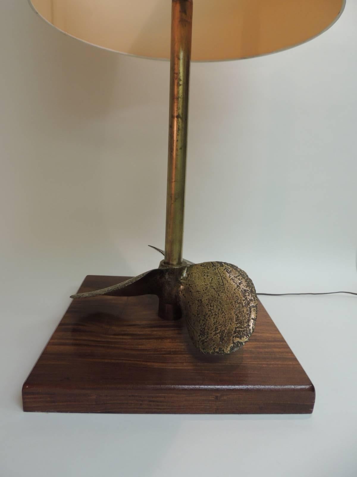  Offered by the Antique Textiles Galleries:
Vintage monumental brass nautical/Maritime boat propeller table lamp. The shade needs to be replace. A few bents around. Comes with the lamp.  Polished brass fittings. One light bulb socket. Mounted on a